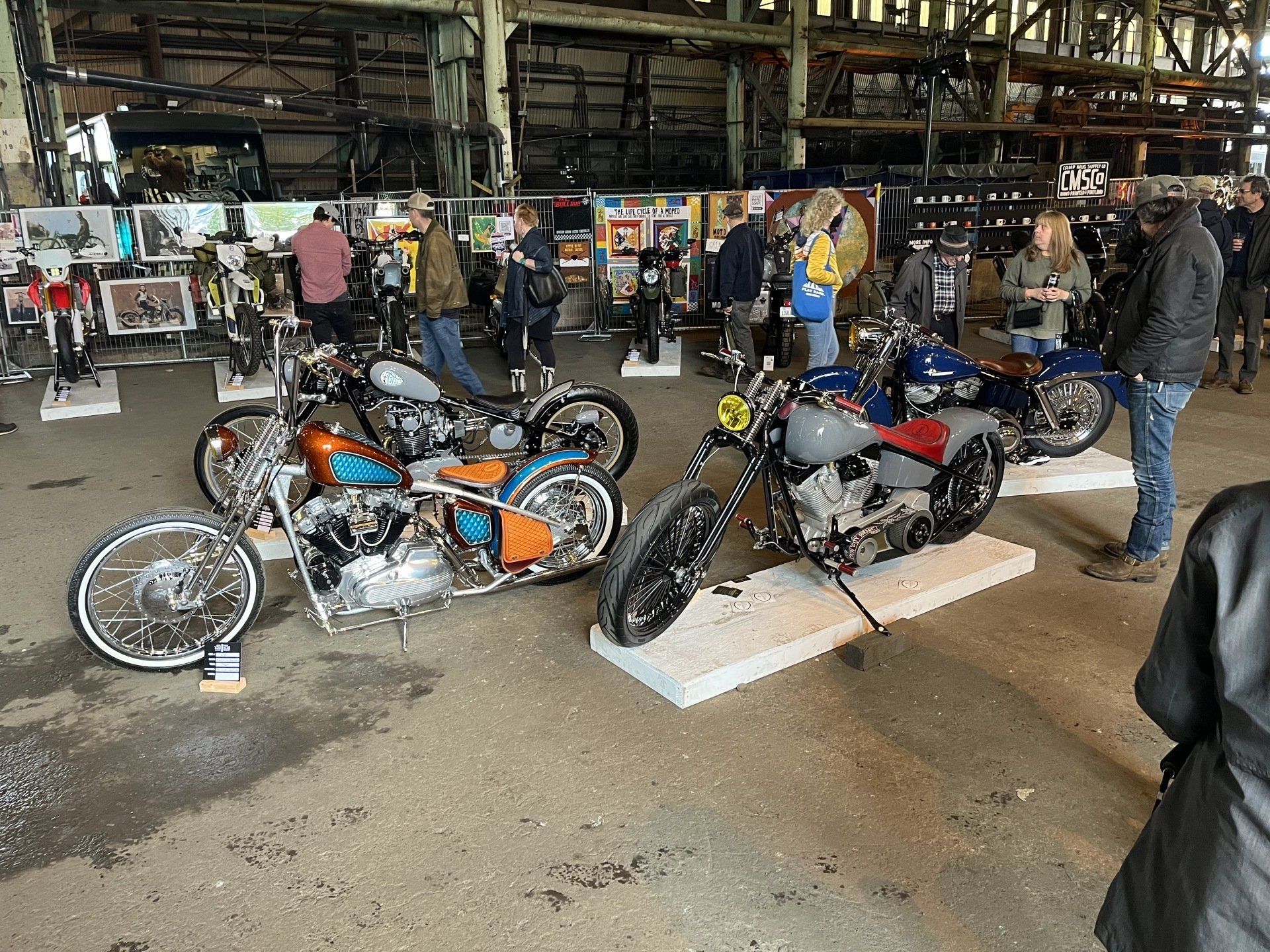 A group of people are standing around a row of motorcycles on display.