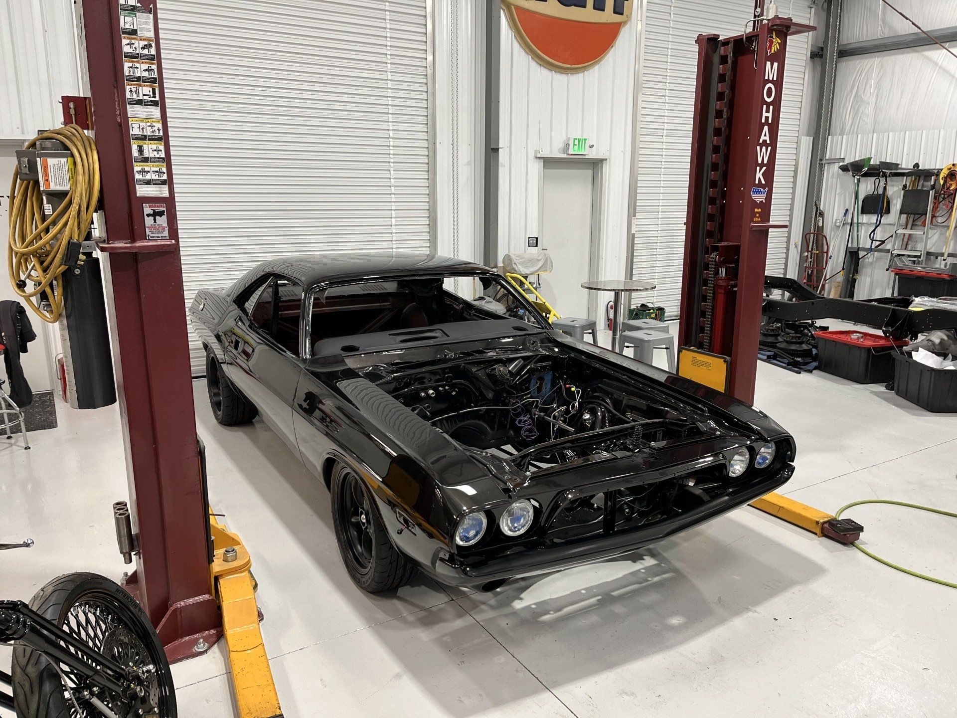 A black car is sitting on a lift in a garage.
