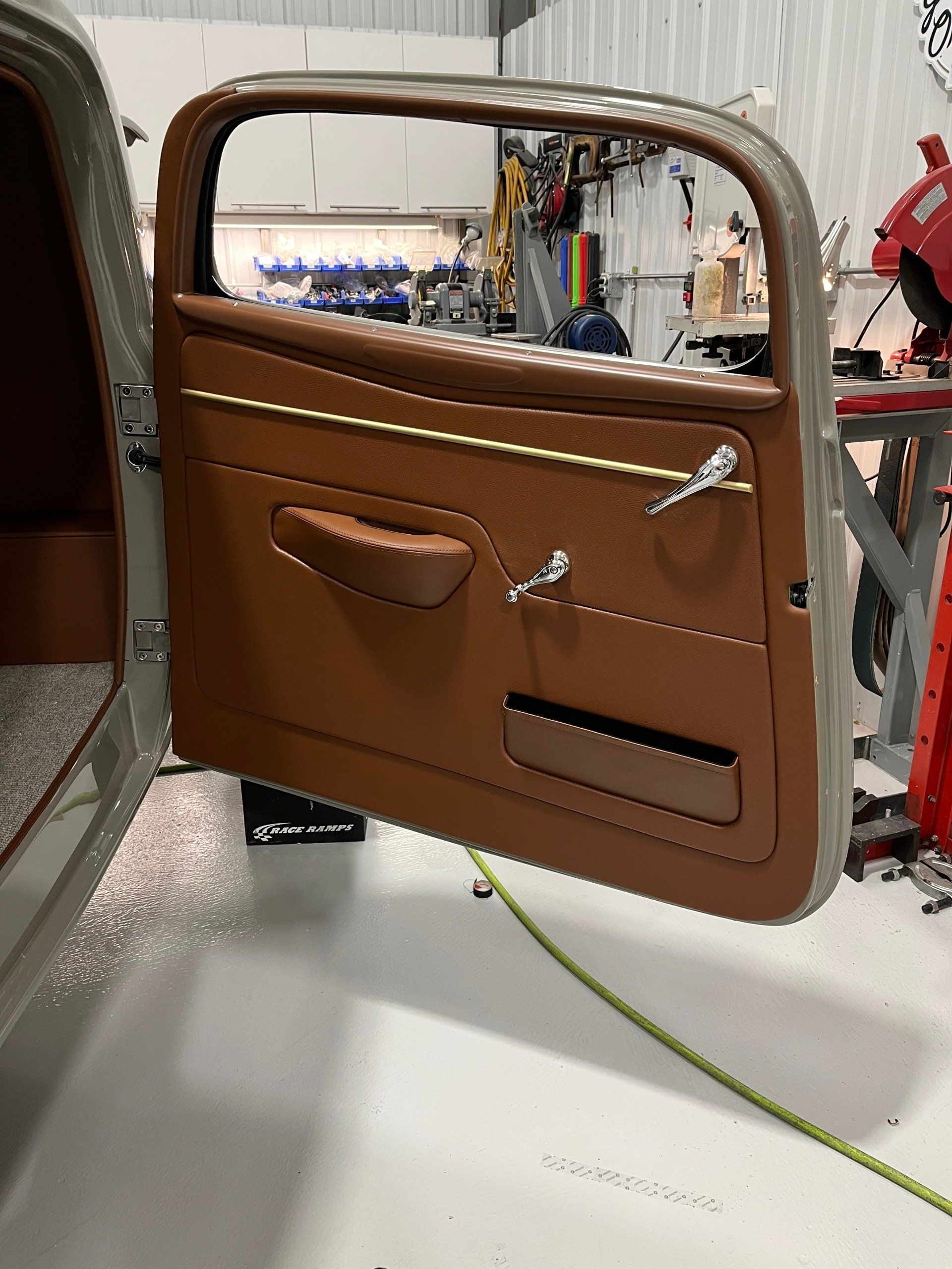A car door with a brown trim is open in a garage
