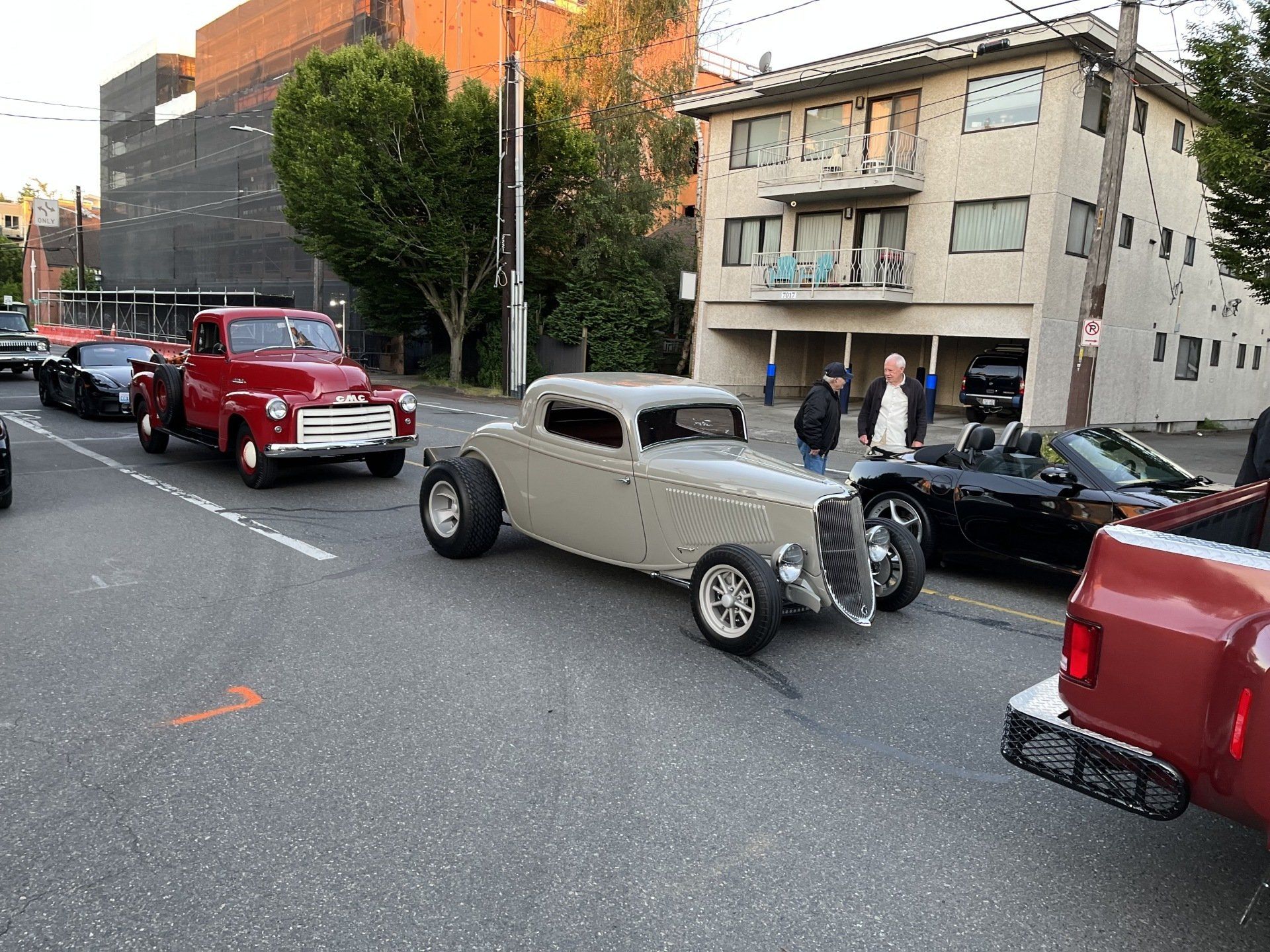 A row of cars are parked on the side of the road in front of a building.