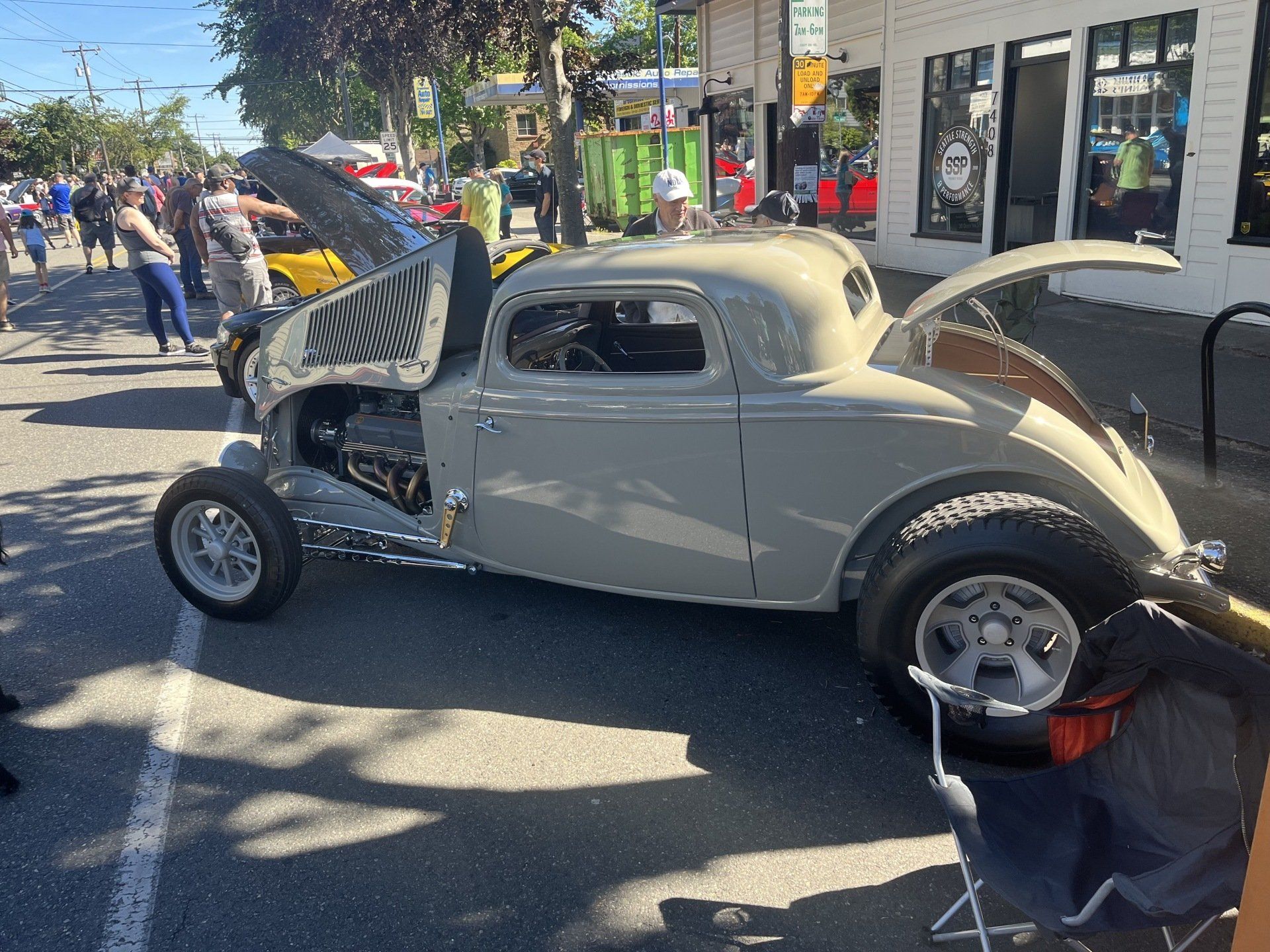 A car with the hood up is parked on the side of the road.