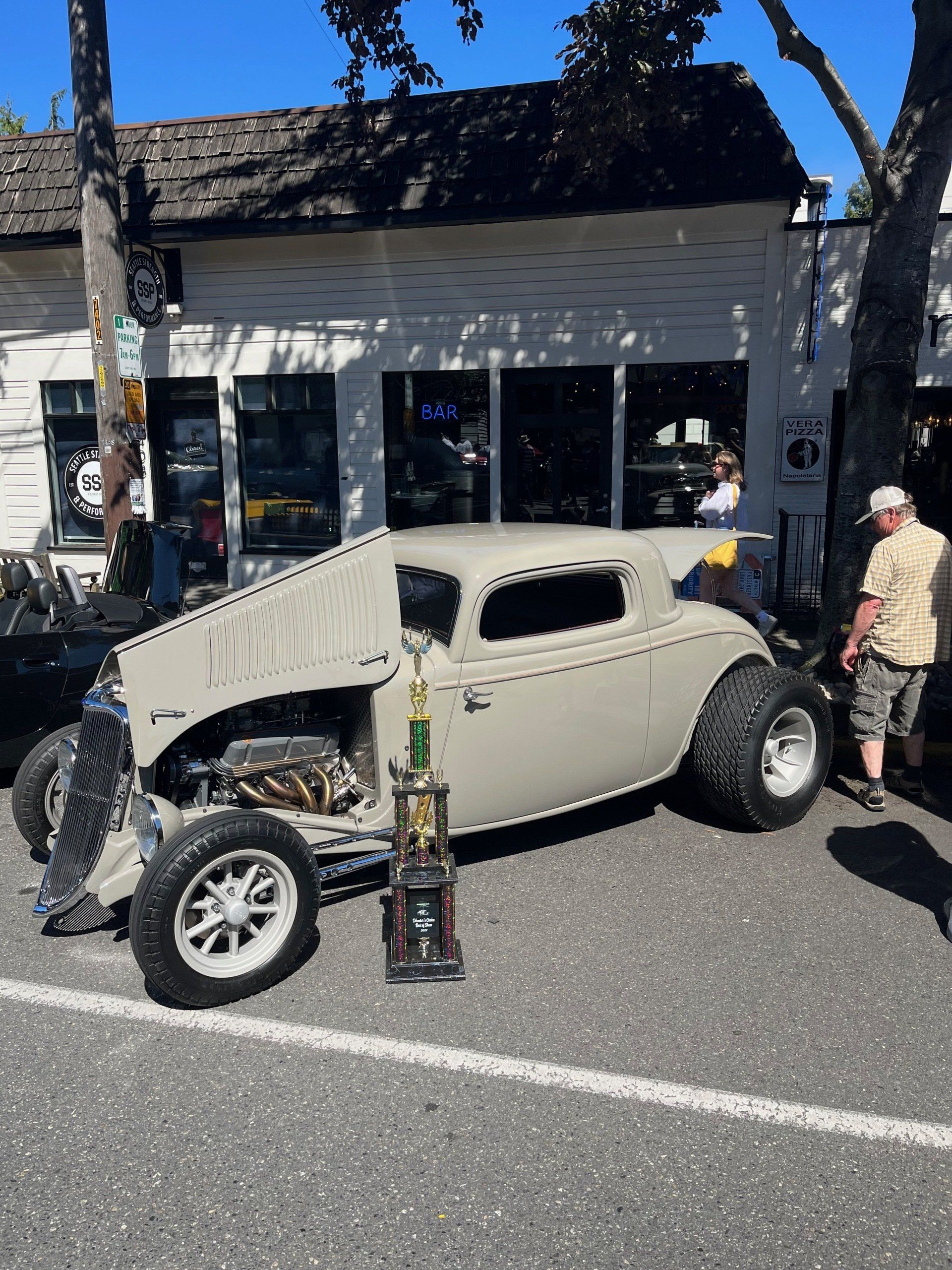 A car with the hood up is parked in front of a building