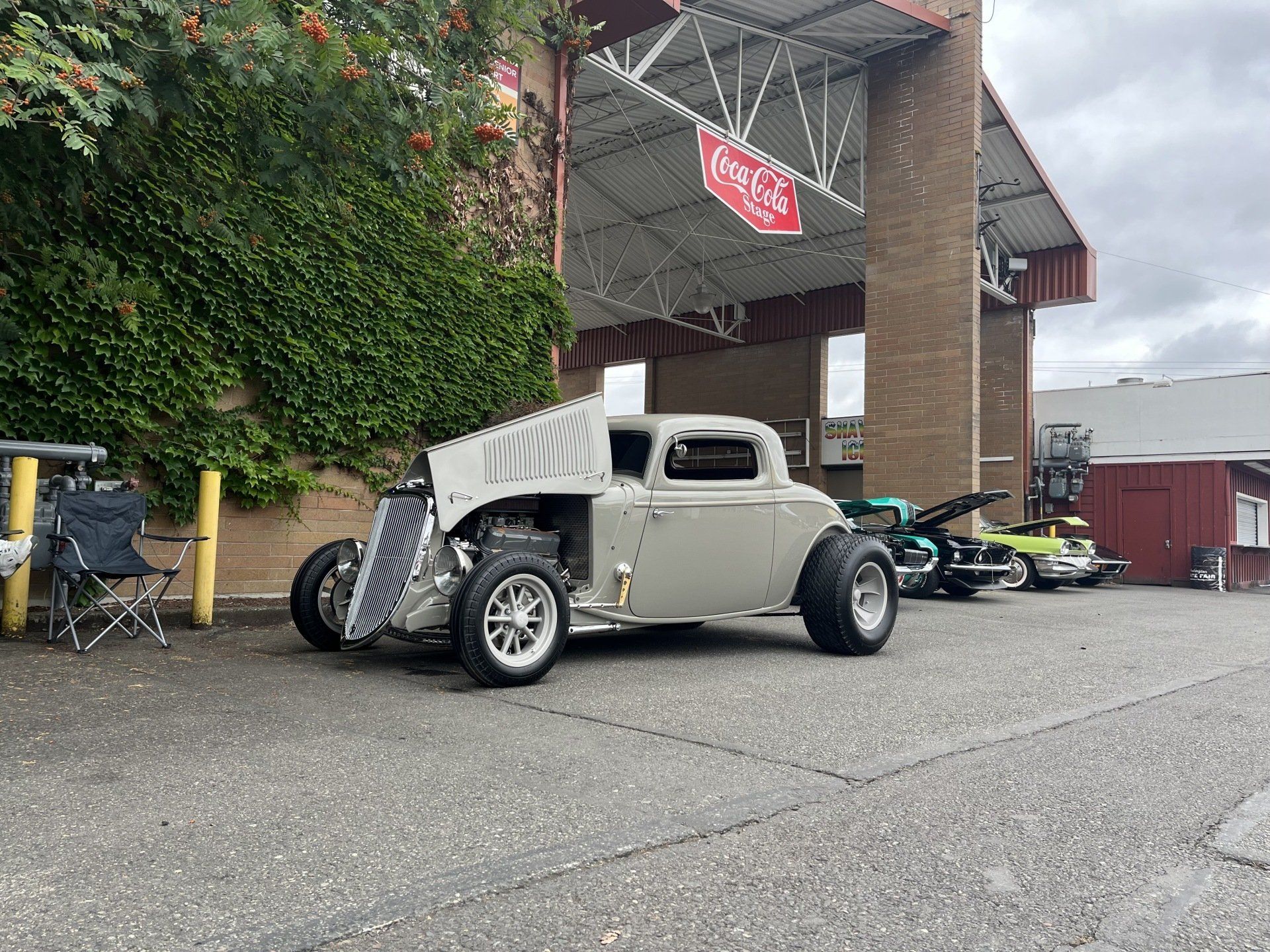 A hot rod is parked in a parking lot in front of a building.