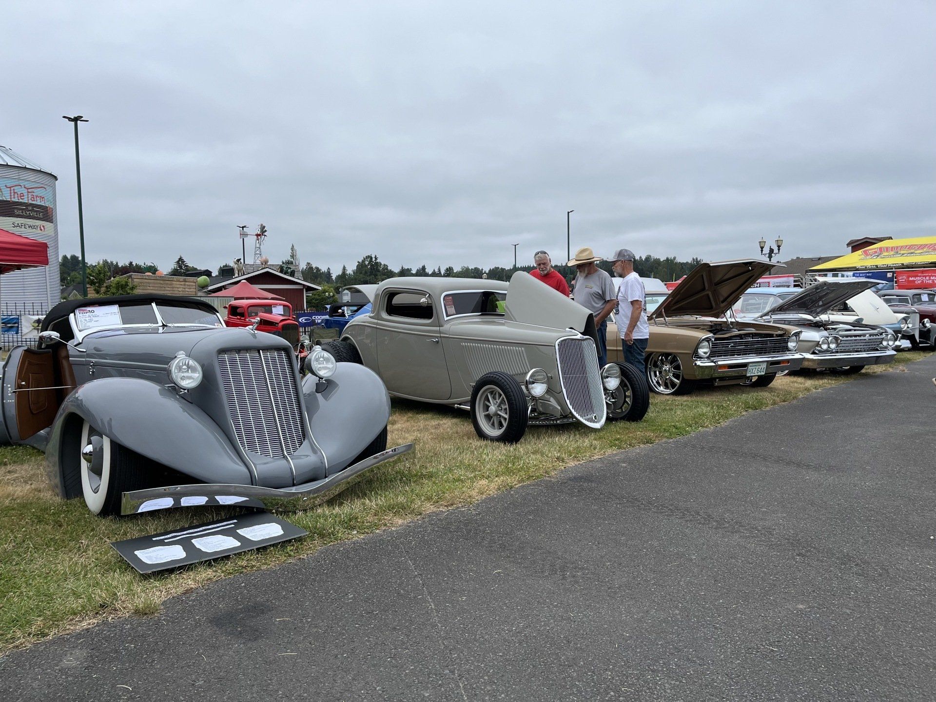 A row of old cars are parked on the side of the road at a car show.