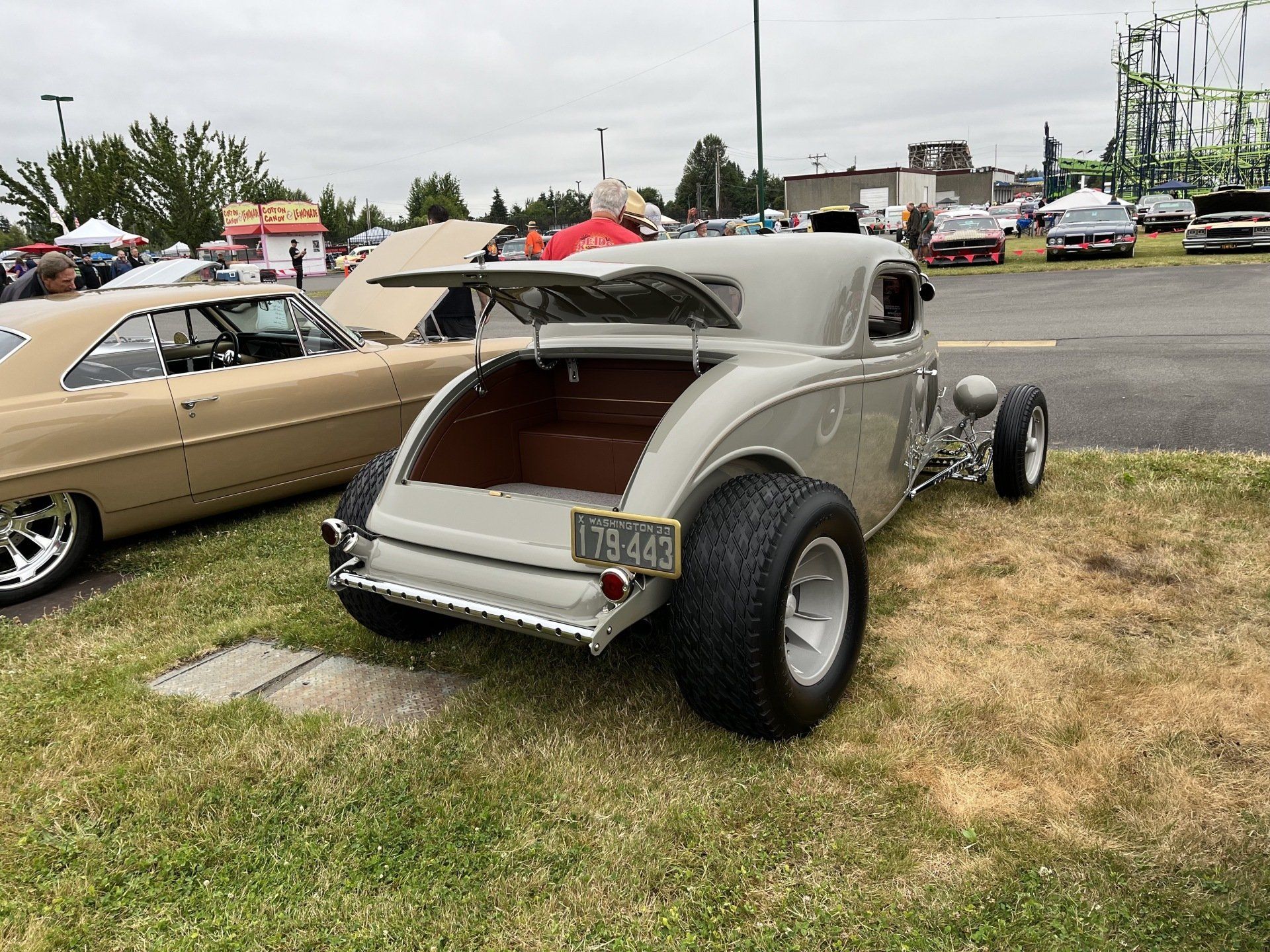 A white hot rod is parked in the grass at a car show.