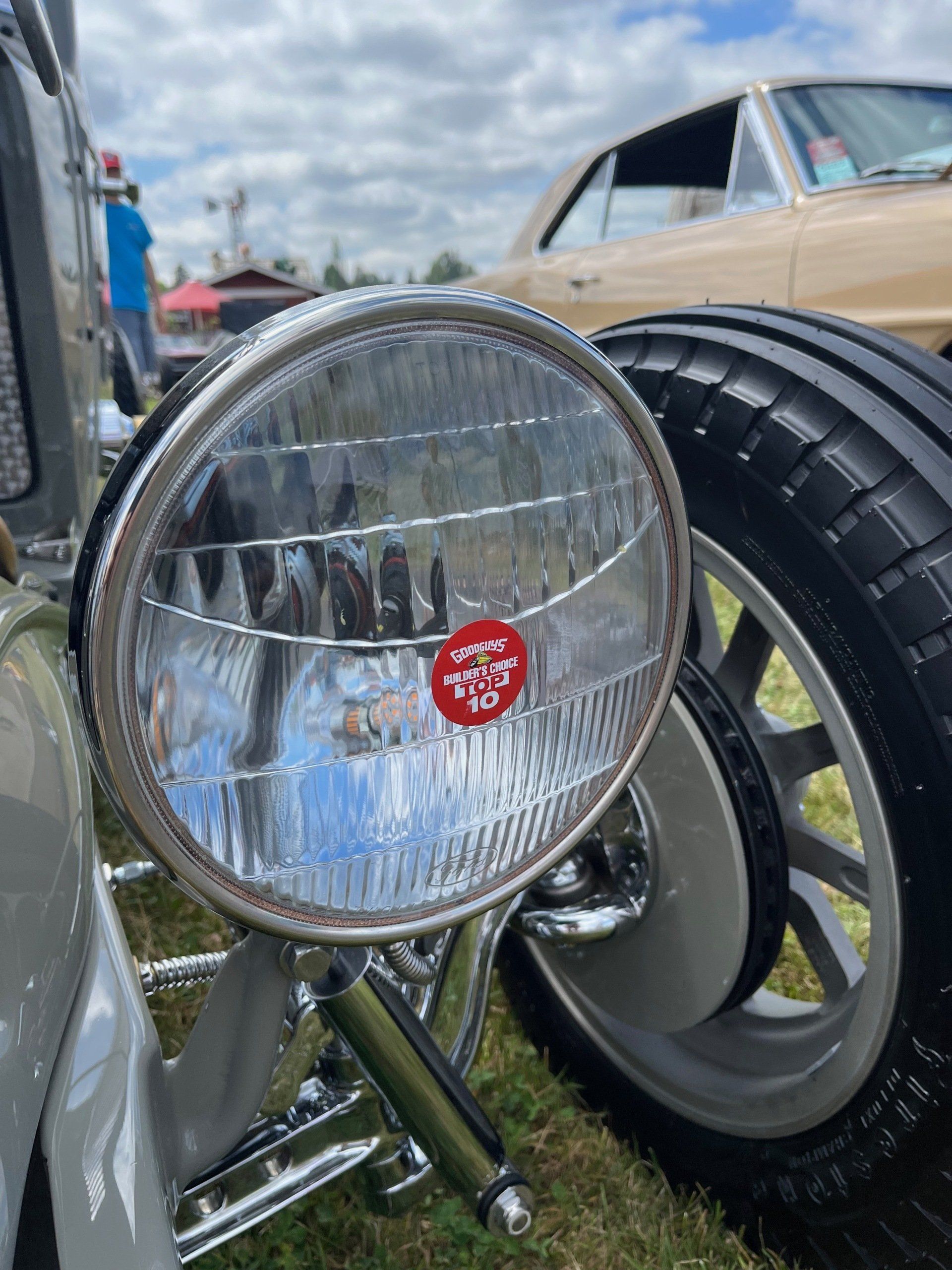 A close up of a headlight on a car with a tire in the background.