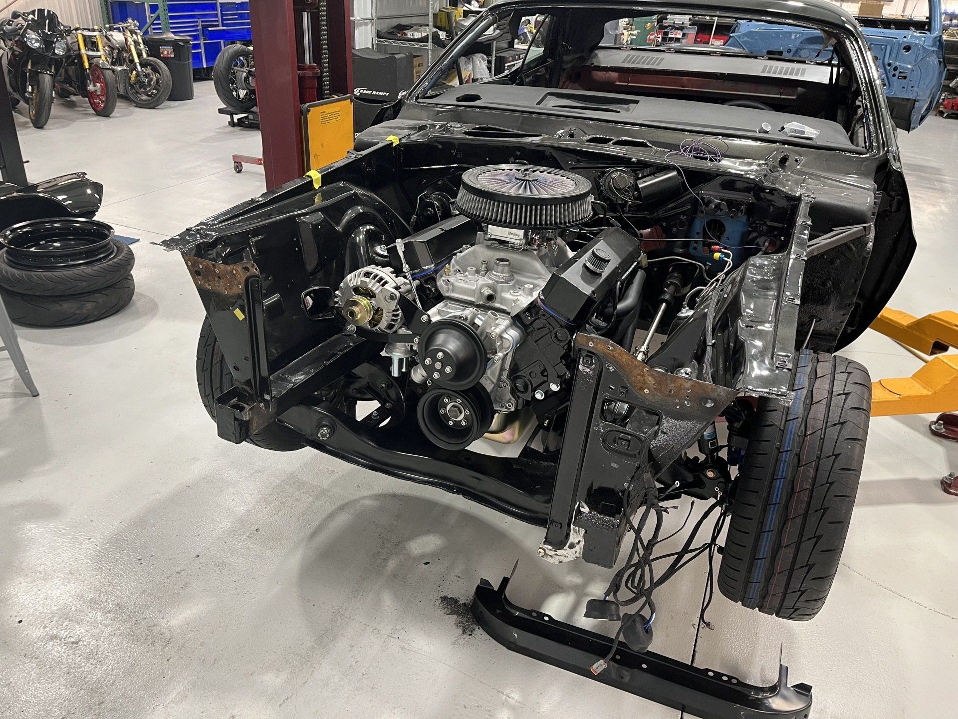 A car with the engine removed is sitting on a lift in a garage.