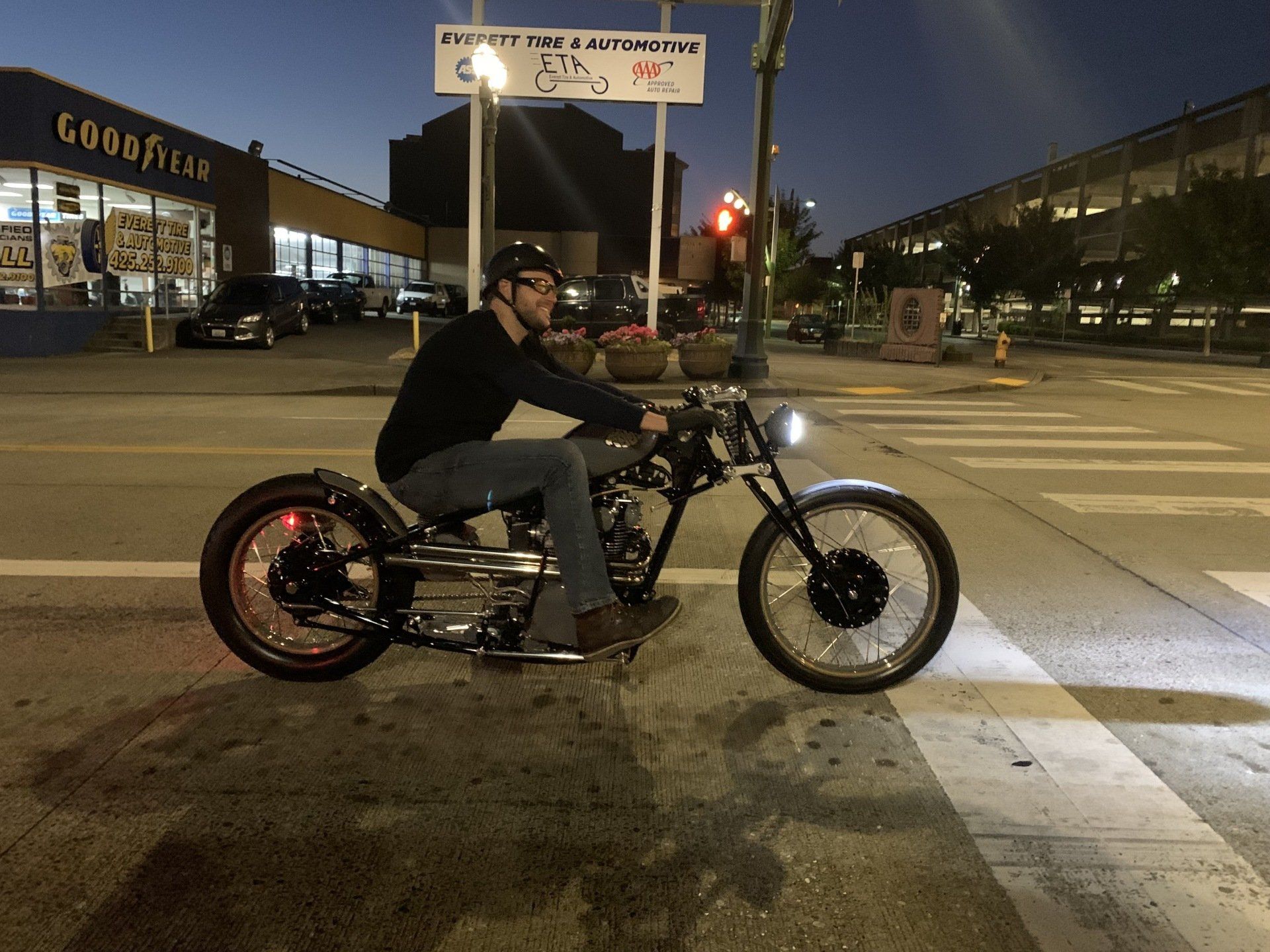 A man is riding a motorcycle in front of a goodyear store