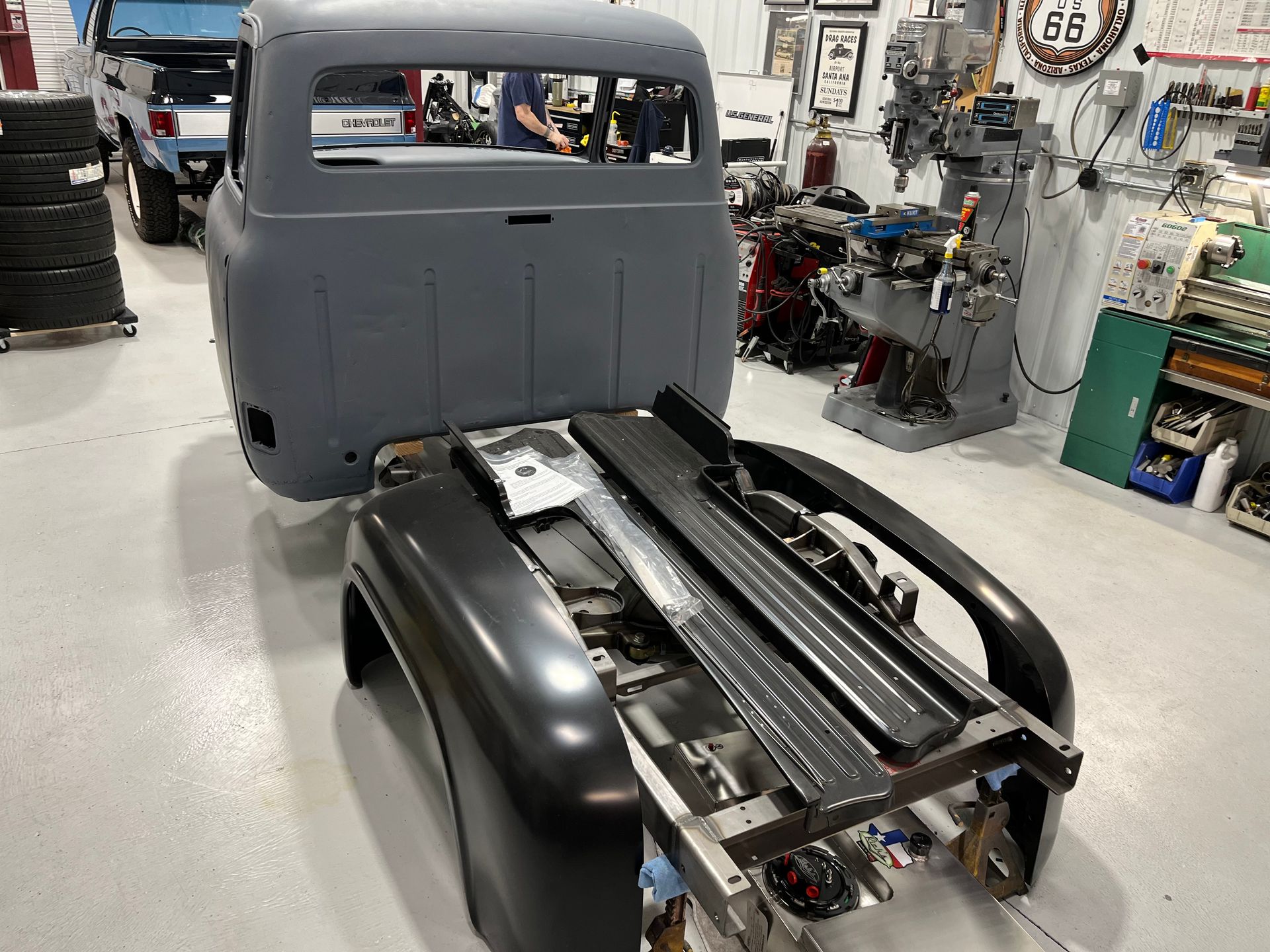 A gray truck is being built in a garage.