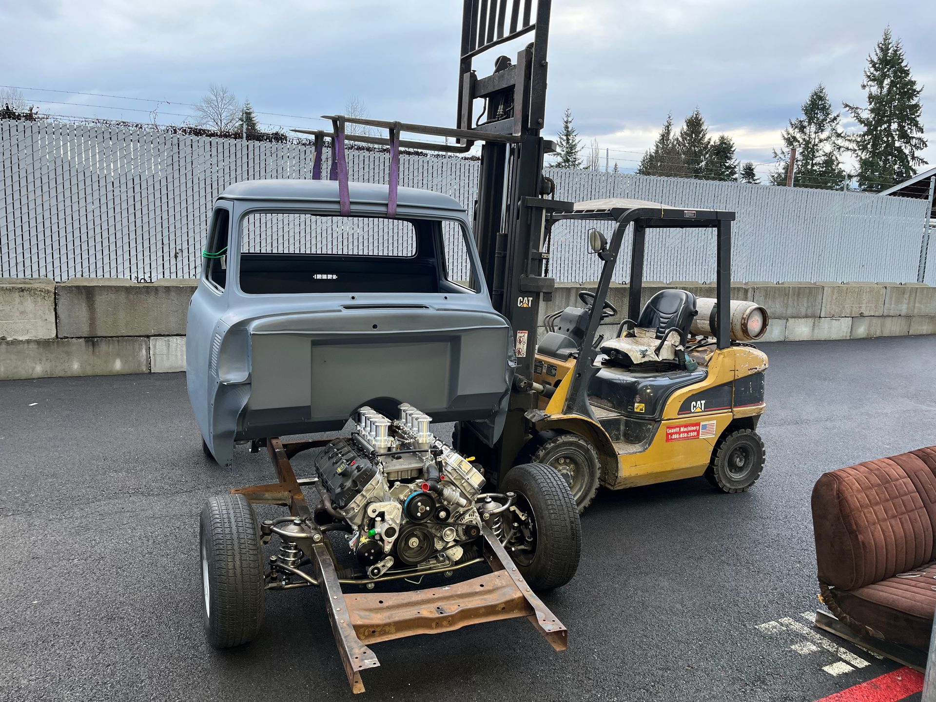 A forklift is carrying a truck with a engine on it.