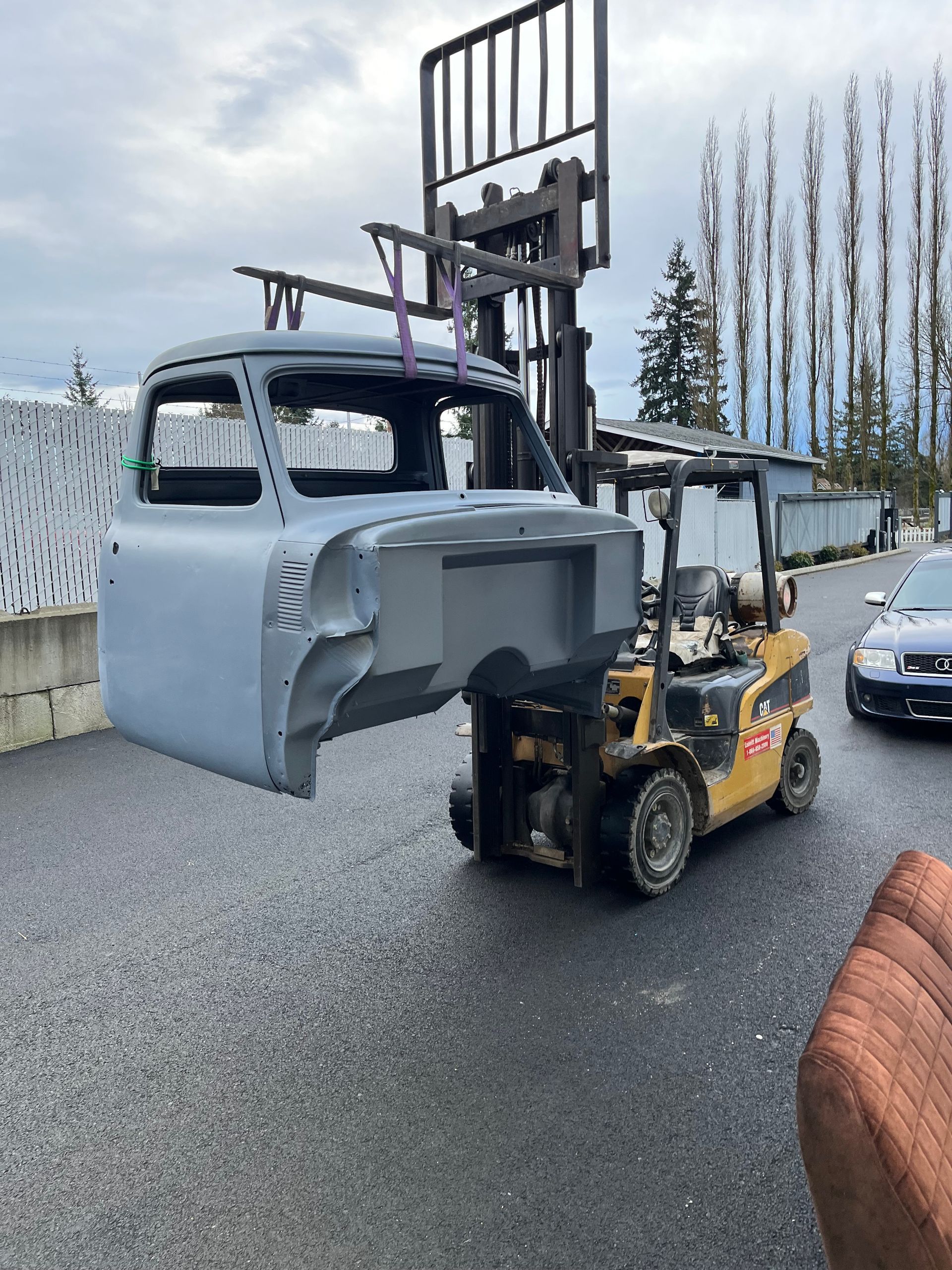 A forklift is lifting the hood of a truck.