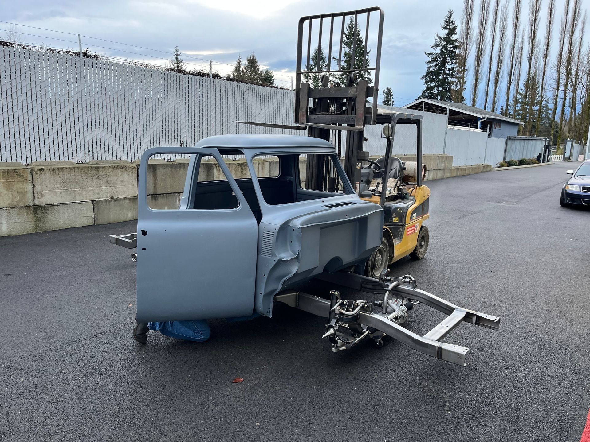 A car is being towed by a forklift on a trailer.