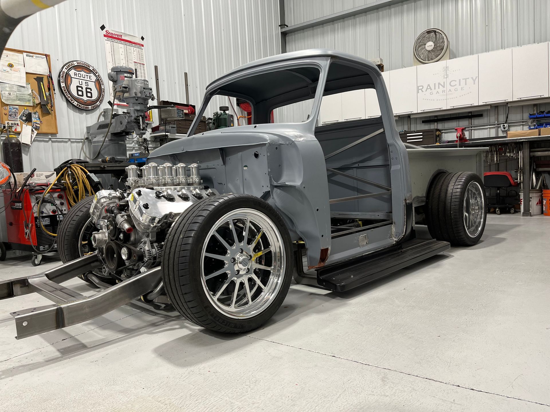 A gray truck is being built in a garage.