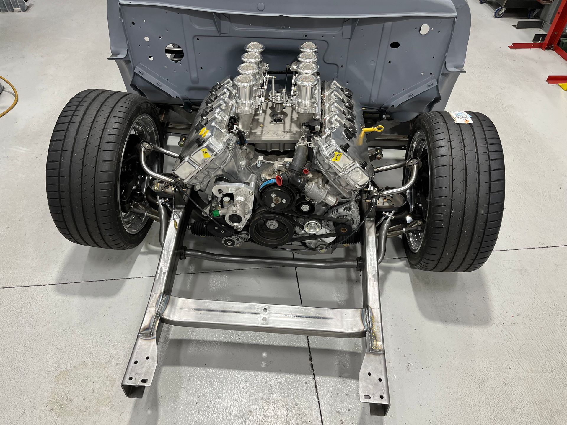 A car engine is sitting on top of a metal frame in a garage.
