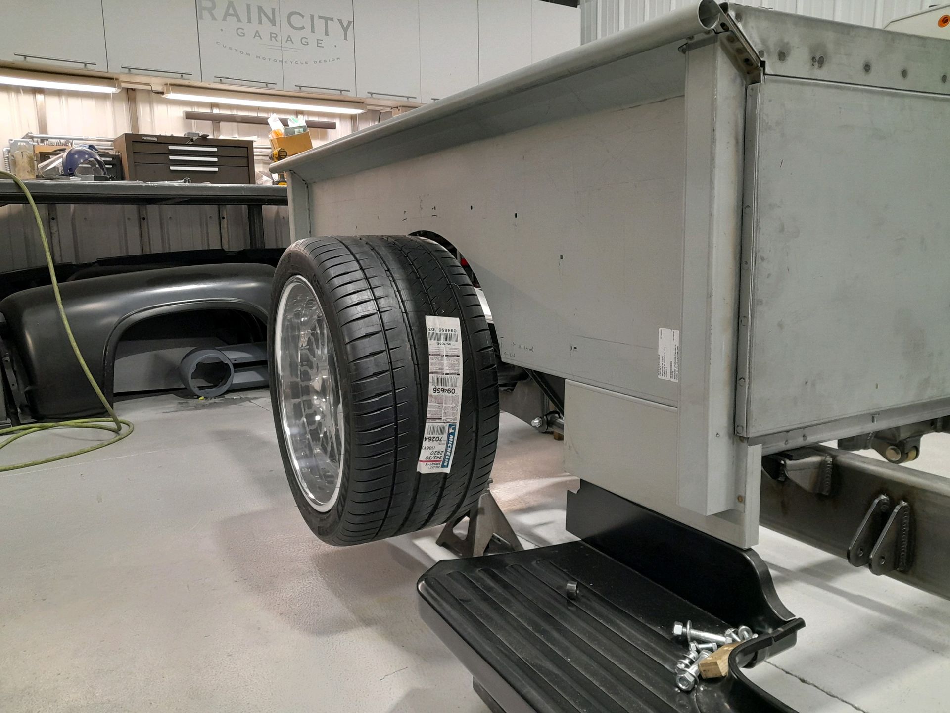 A tire is attached to the back of a truck in a garage.