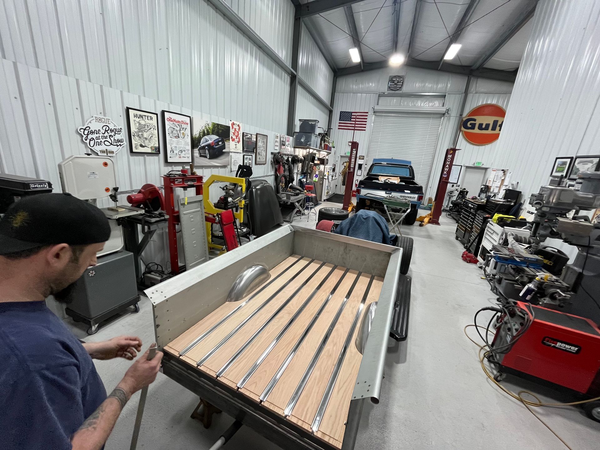A man is working on a truck bed in a garage.