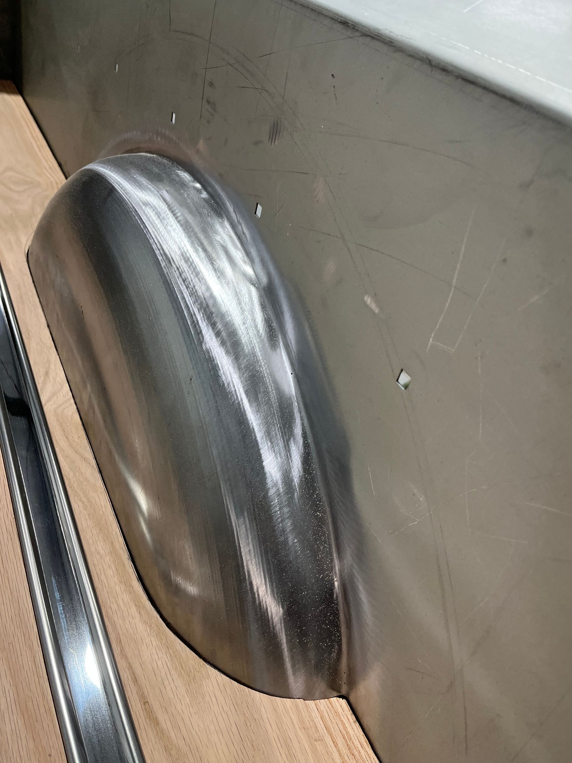 A metal fender is sitting on top of a wooden table.