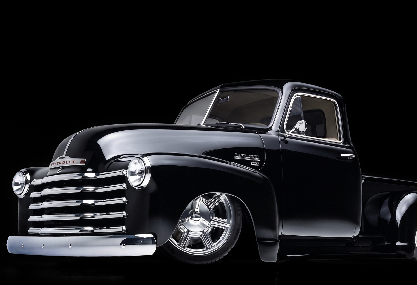 A black car is sitting on a lift in a garage.