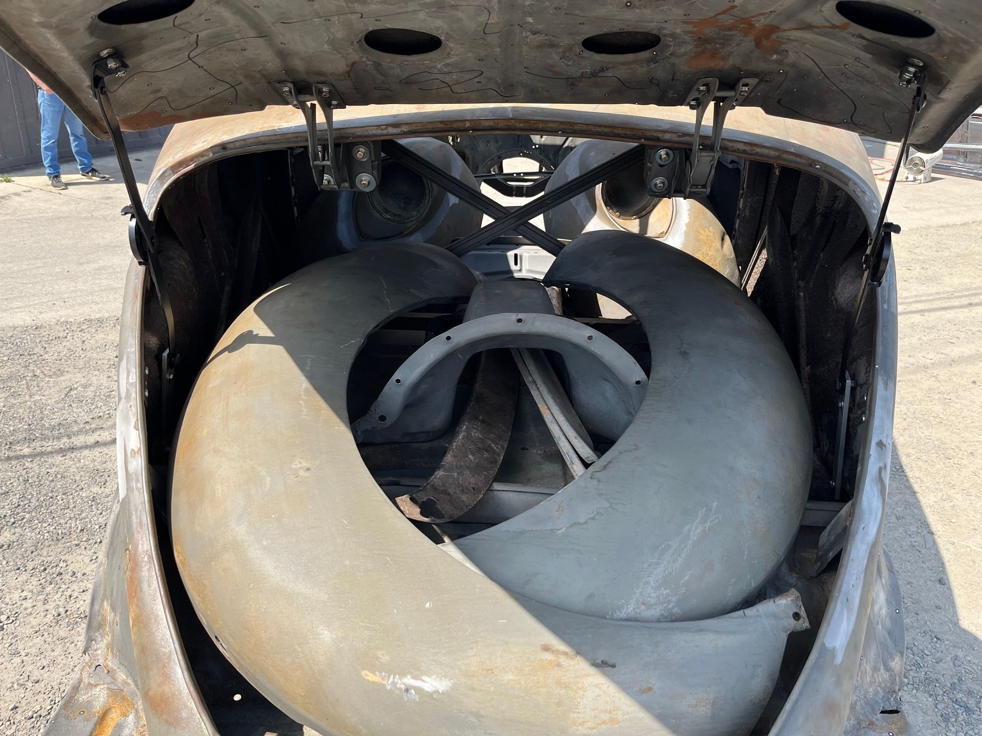 The trunk of an old car has a large tire in it