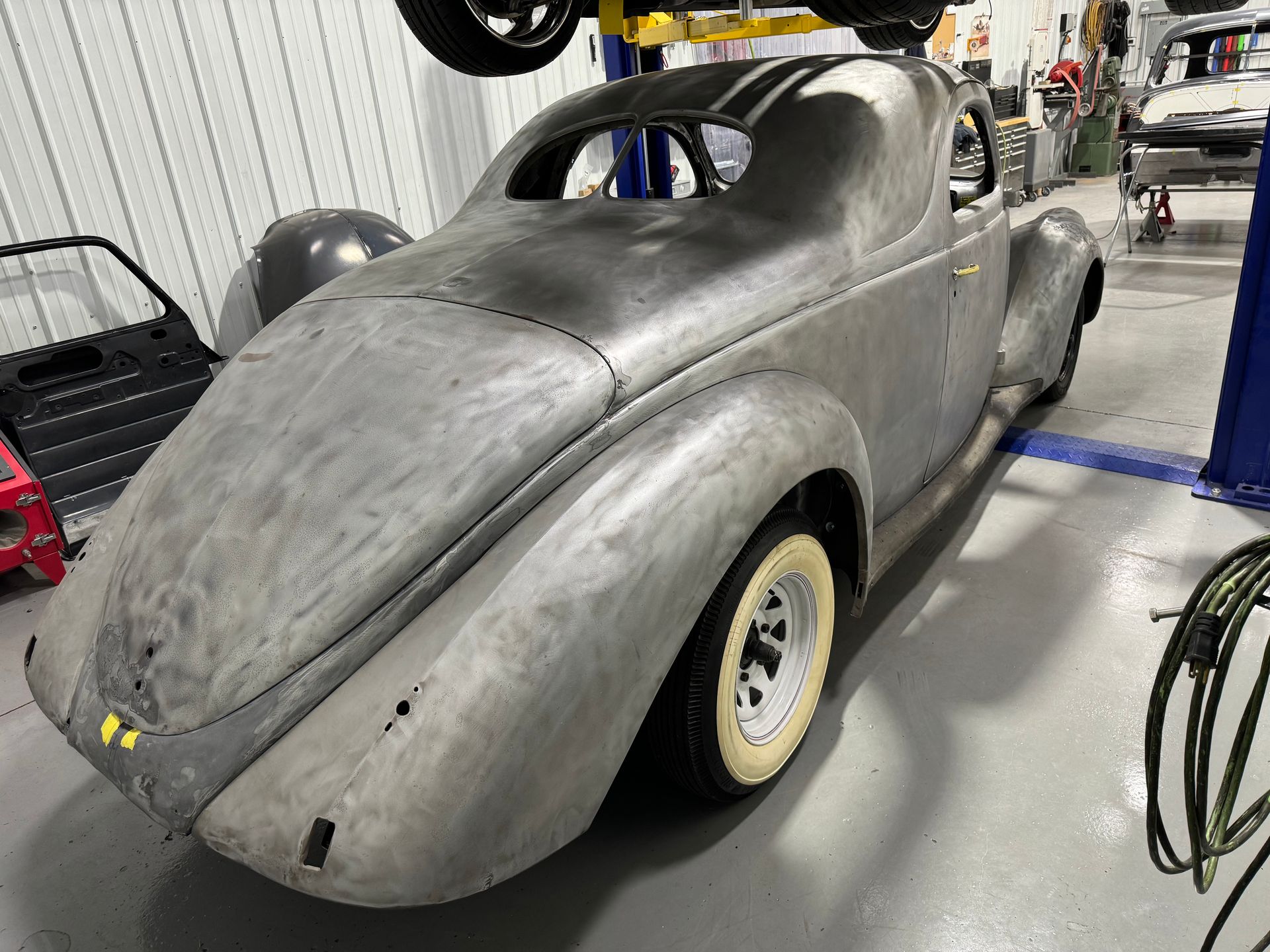 A silver car is sitting on a lift in a garage.