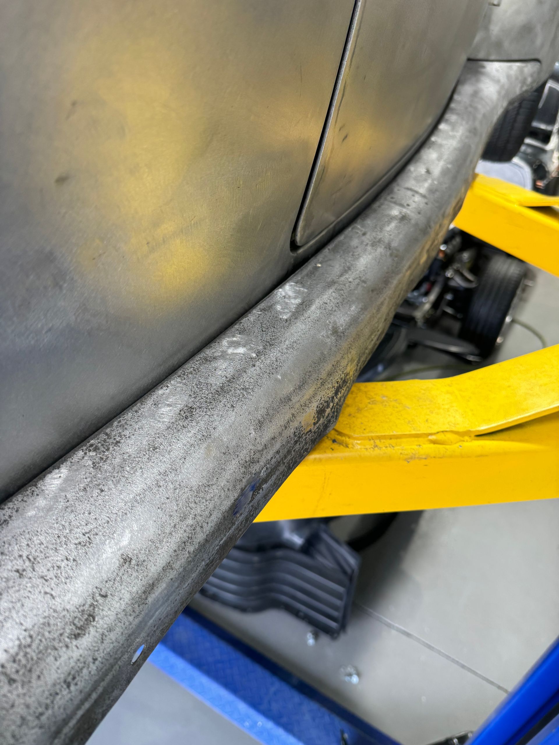 A car is sitting on a yellow lift in a garage.