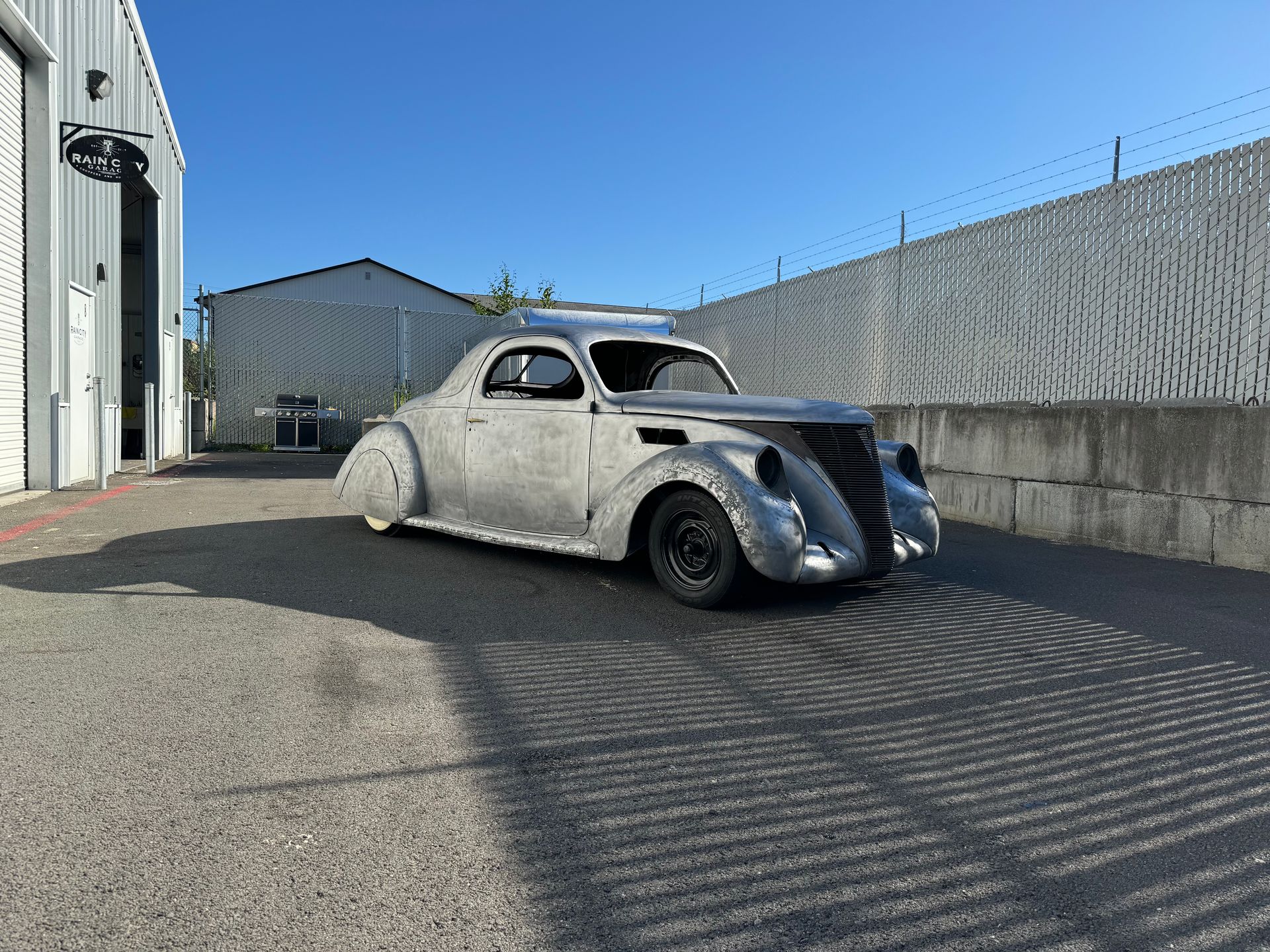 A silver car is parked in a parking lot in front of a building.