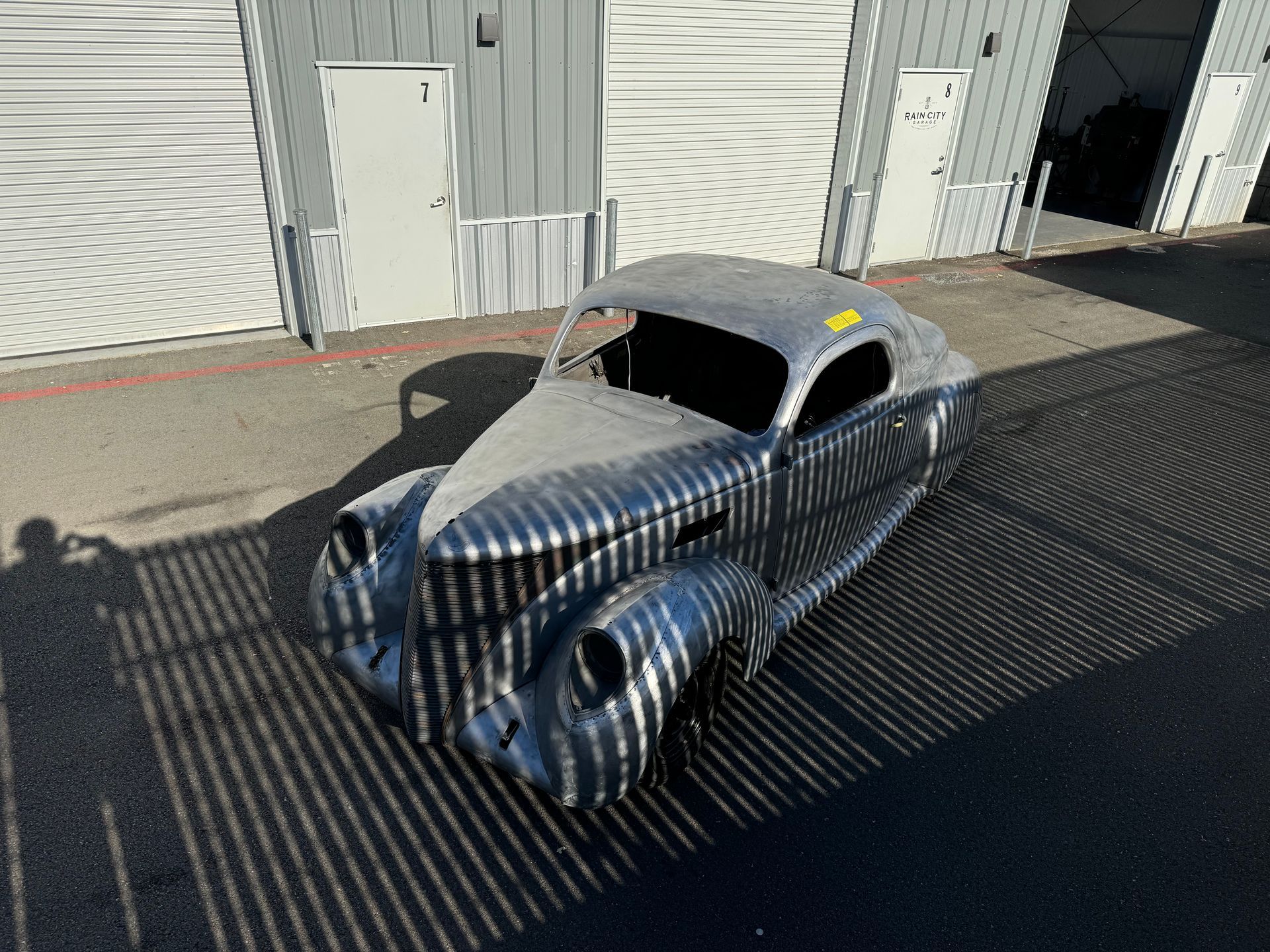 A silver car is parked in front of a garage.