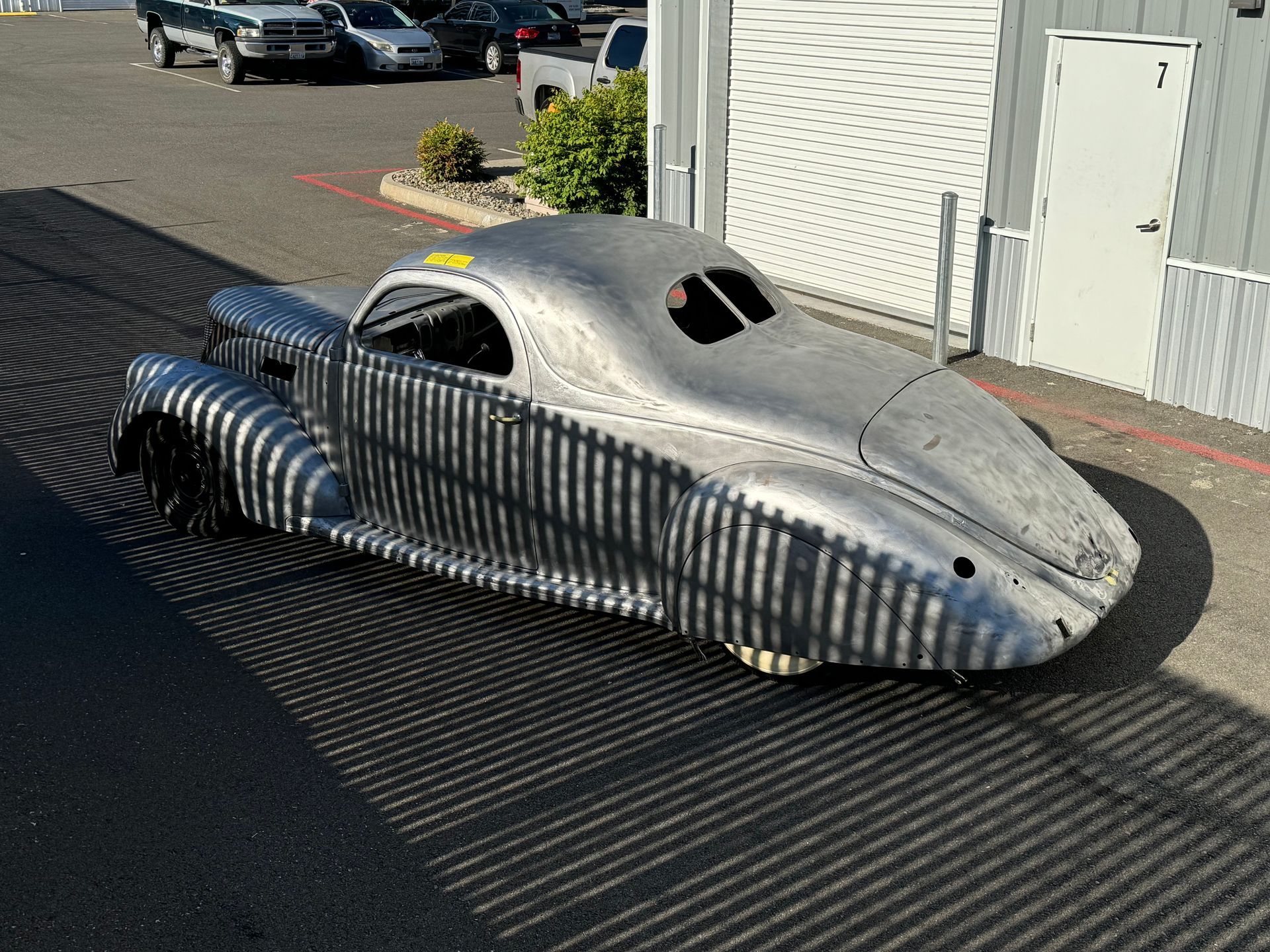 A silver car is parked in front of a garage.