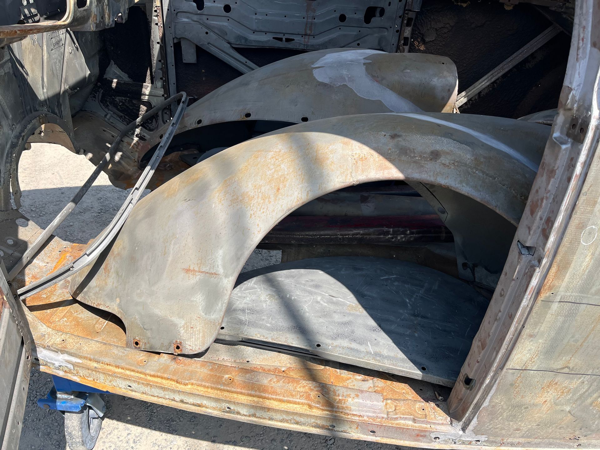 A rusty car with fenders sitting on top of a wooden table.