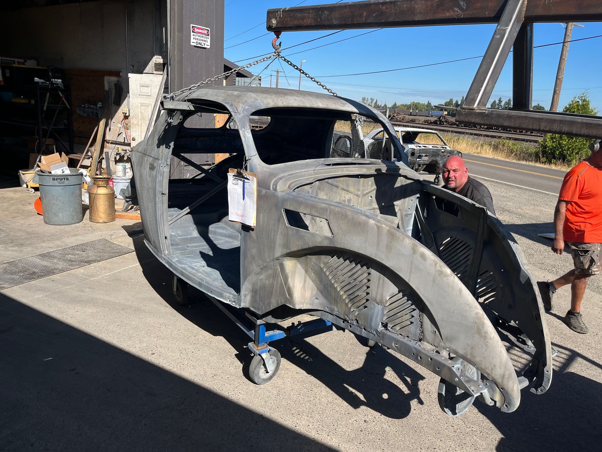 A man is standing next to a car that is being dismantled