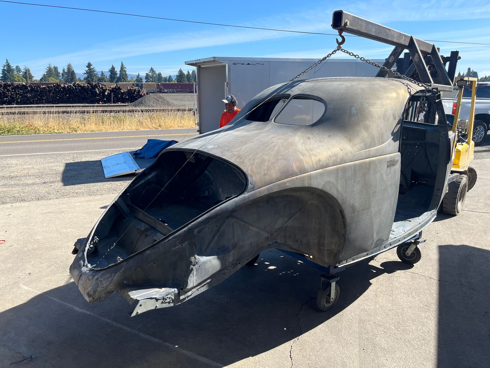 A car is being lifted by a crane in a parking lot