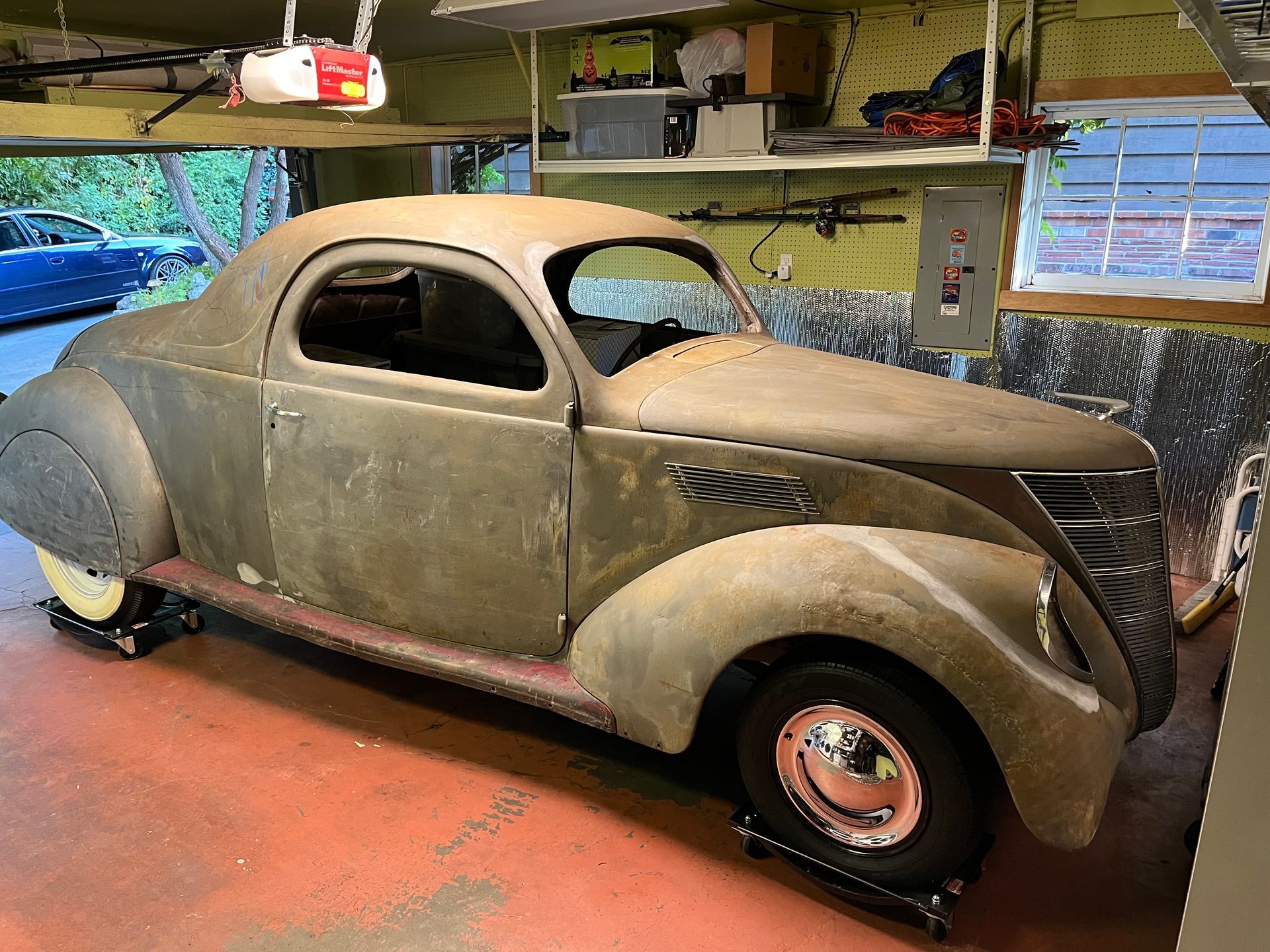 A very old car is parked in a garage.