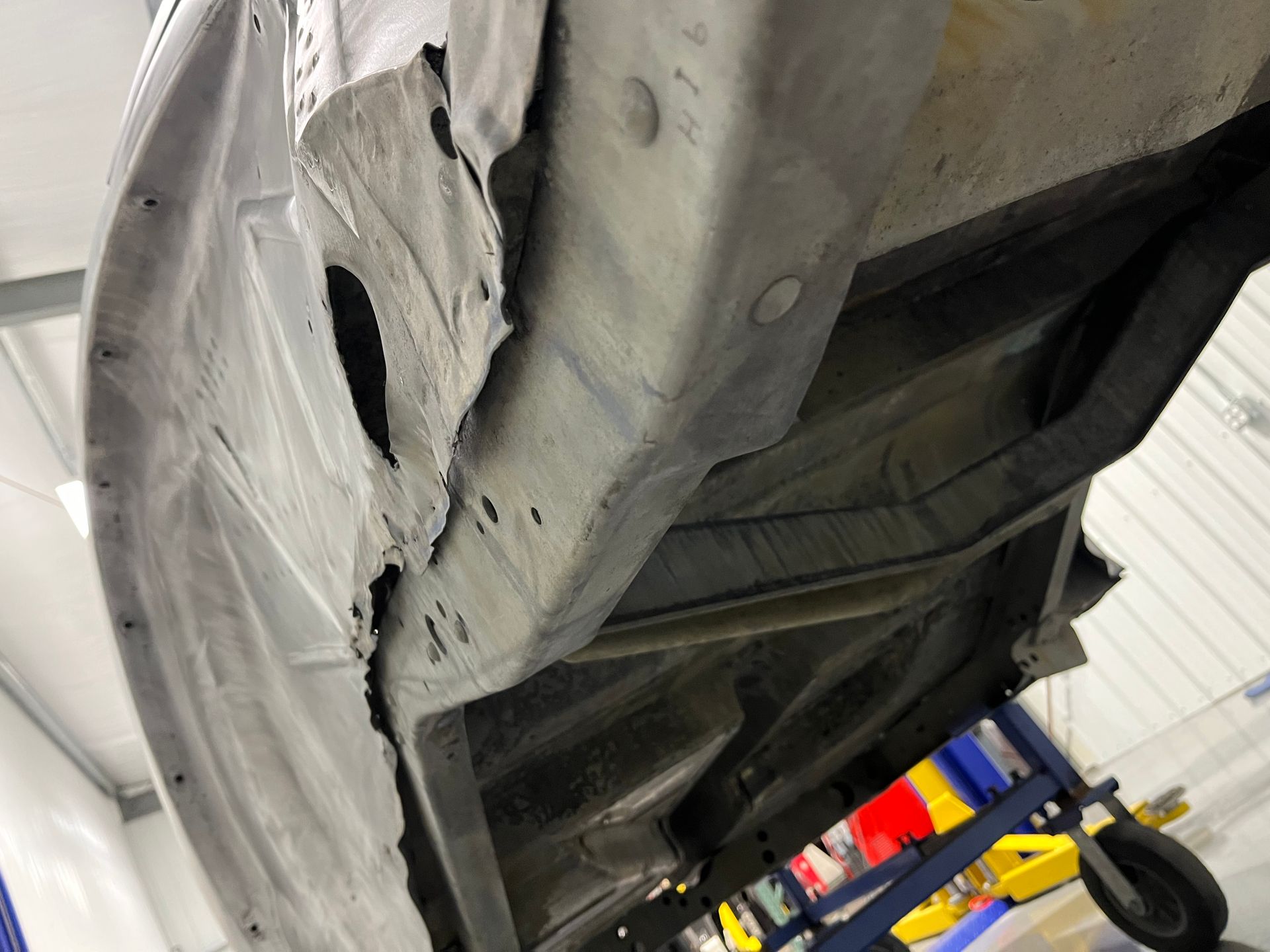 The underside of a car is shown in a garage.