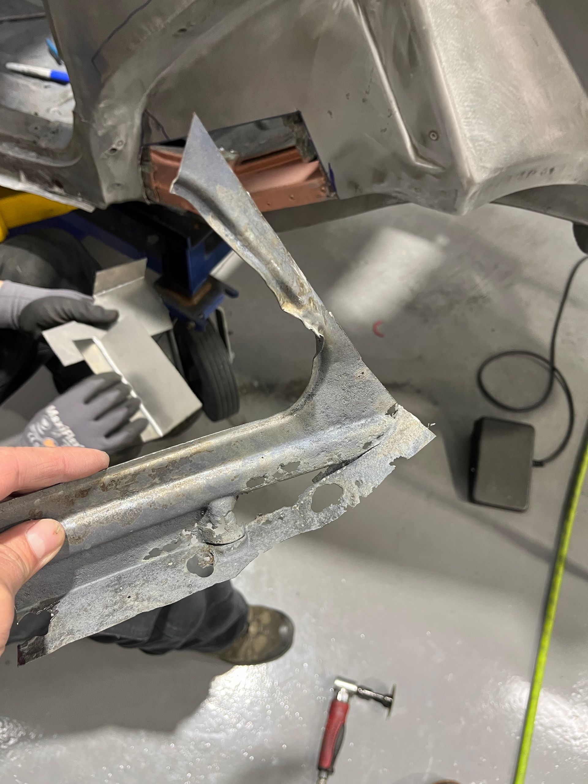 A person is holding a piece of metal in their hand in a garage.