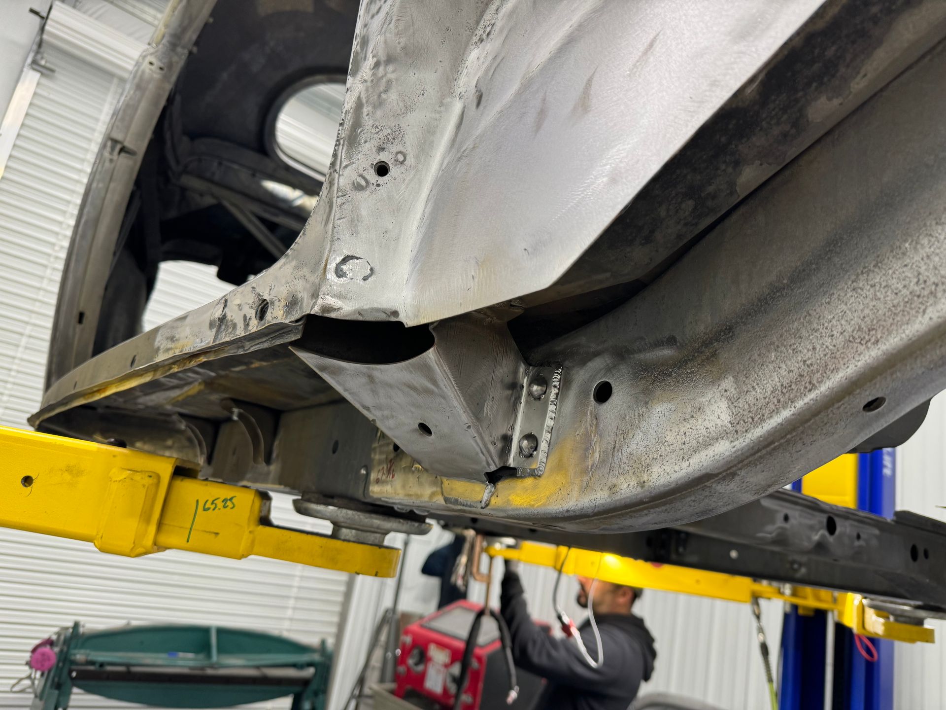 A man is working on the underside of a car on a lift.