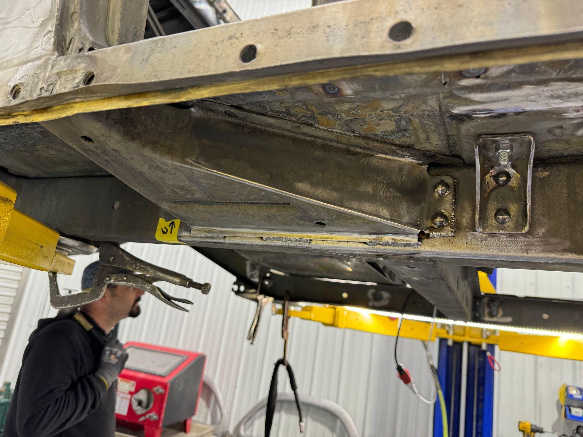 A man is working on the underside of a car on a lift.