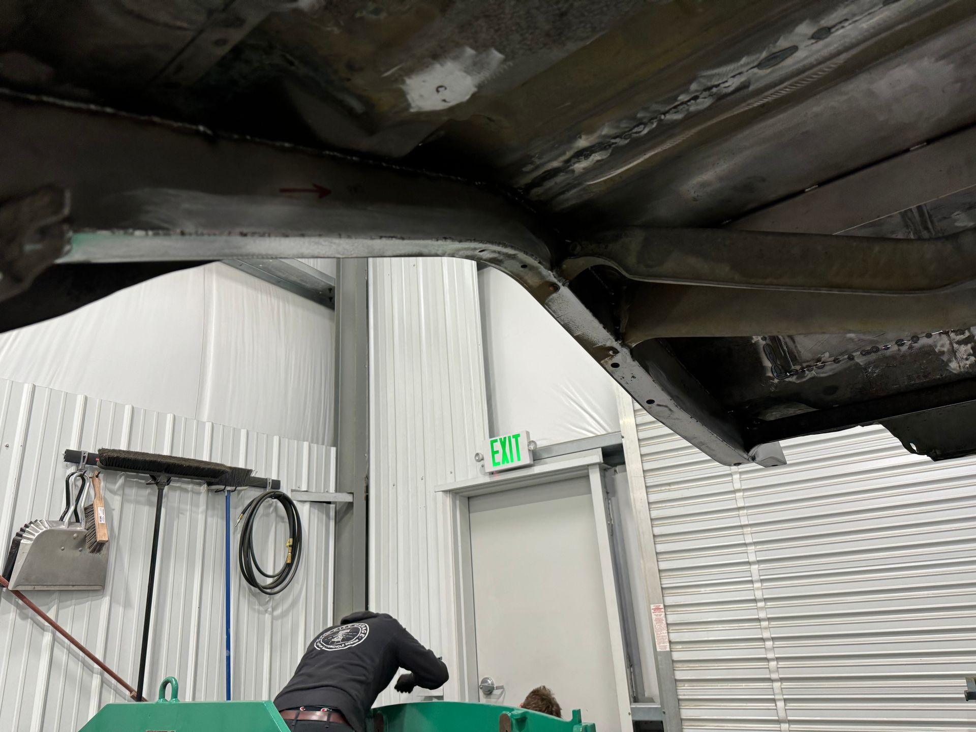 A man is working underneath a car in a garage