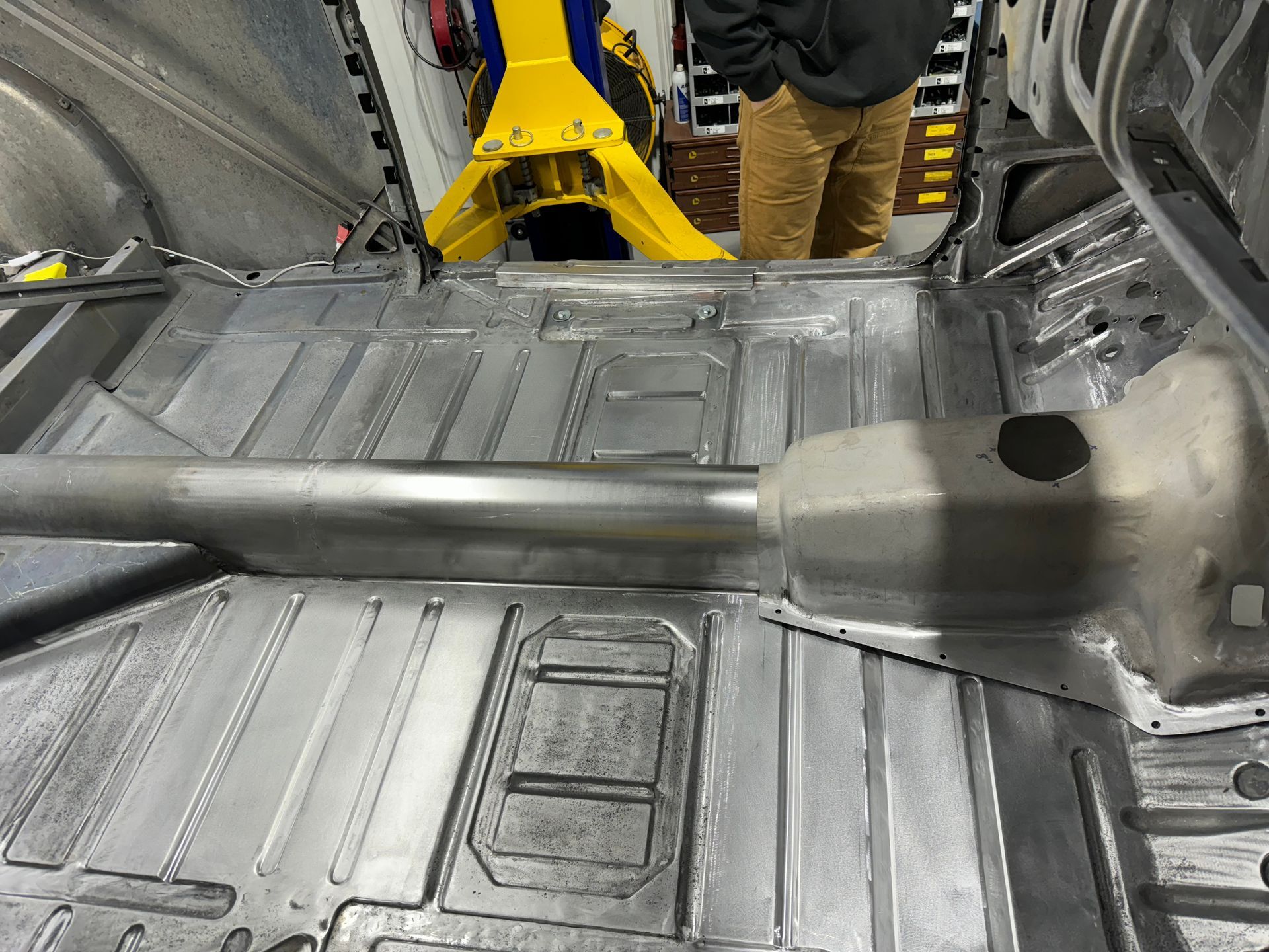 A man is standing in the back of a car in a garage.