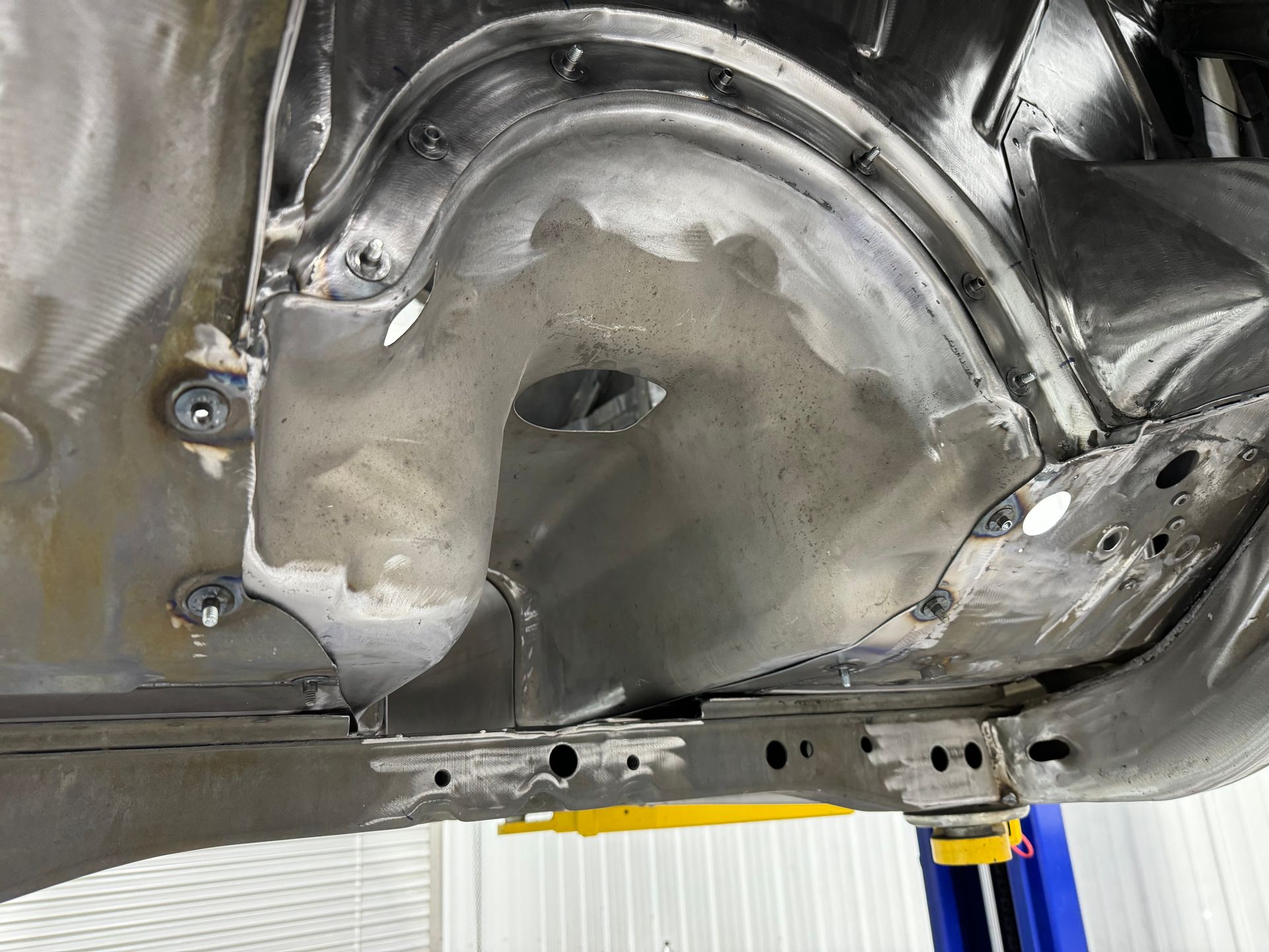 A close up of the underside of a car on a lift.