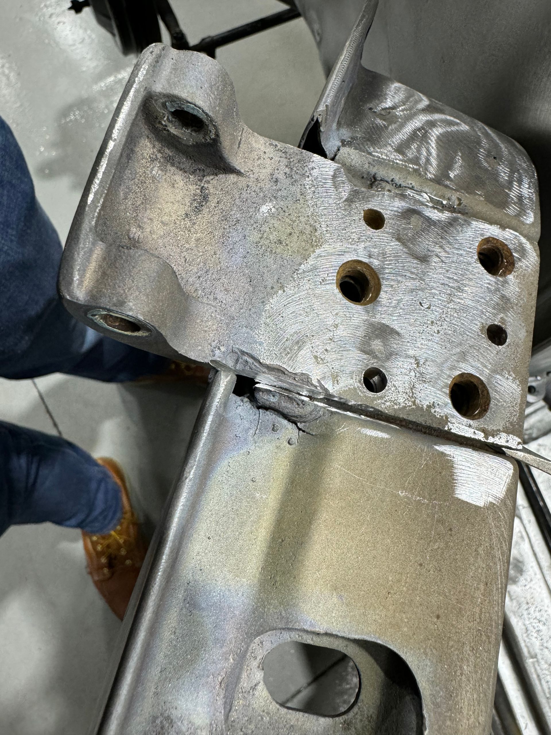 A person is standing next to a piece of metal with holes in it.