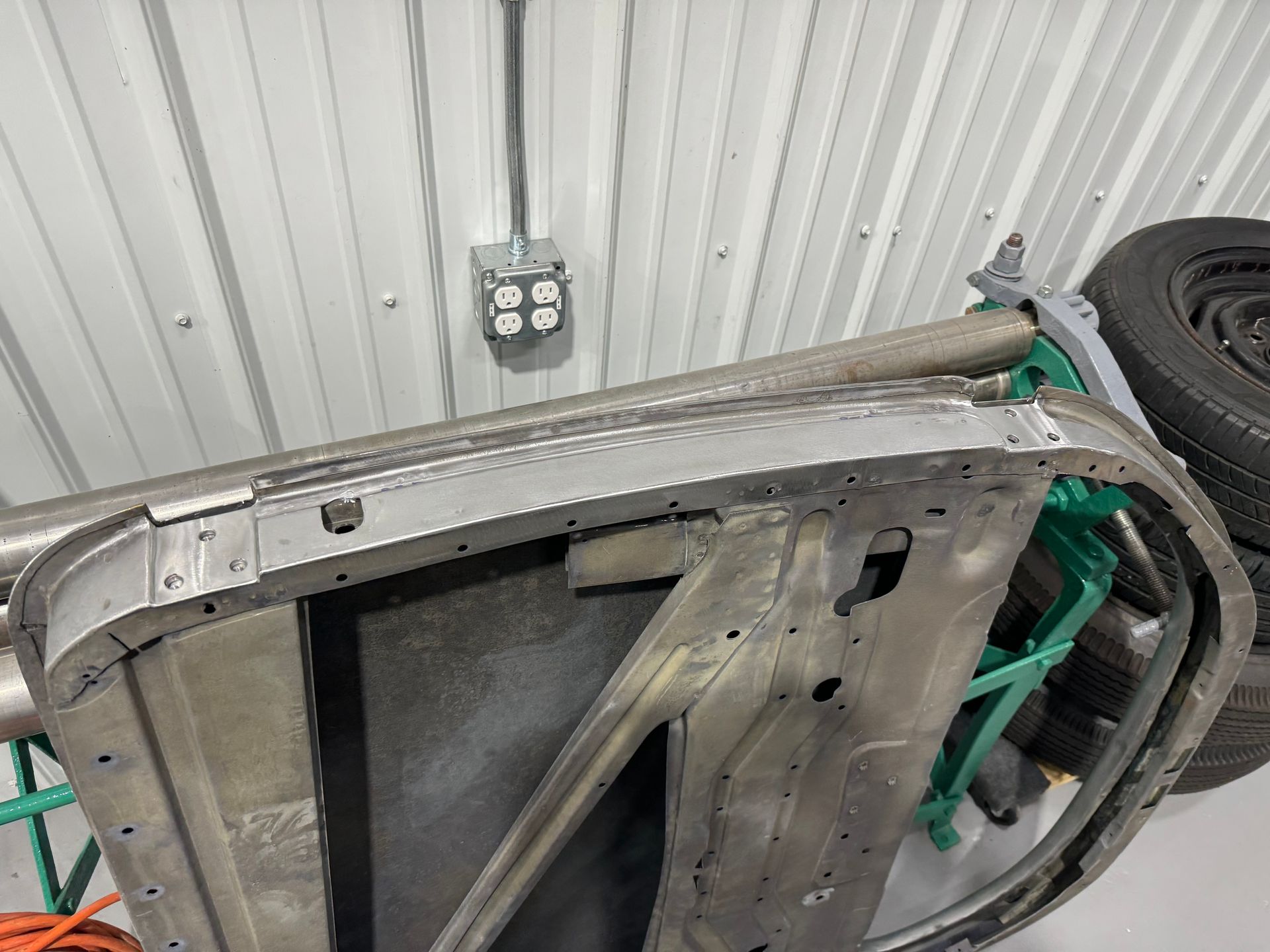 A car door is sitting on top of a green stand in a garage.