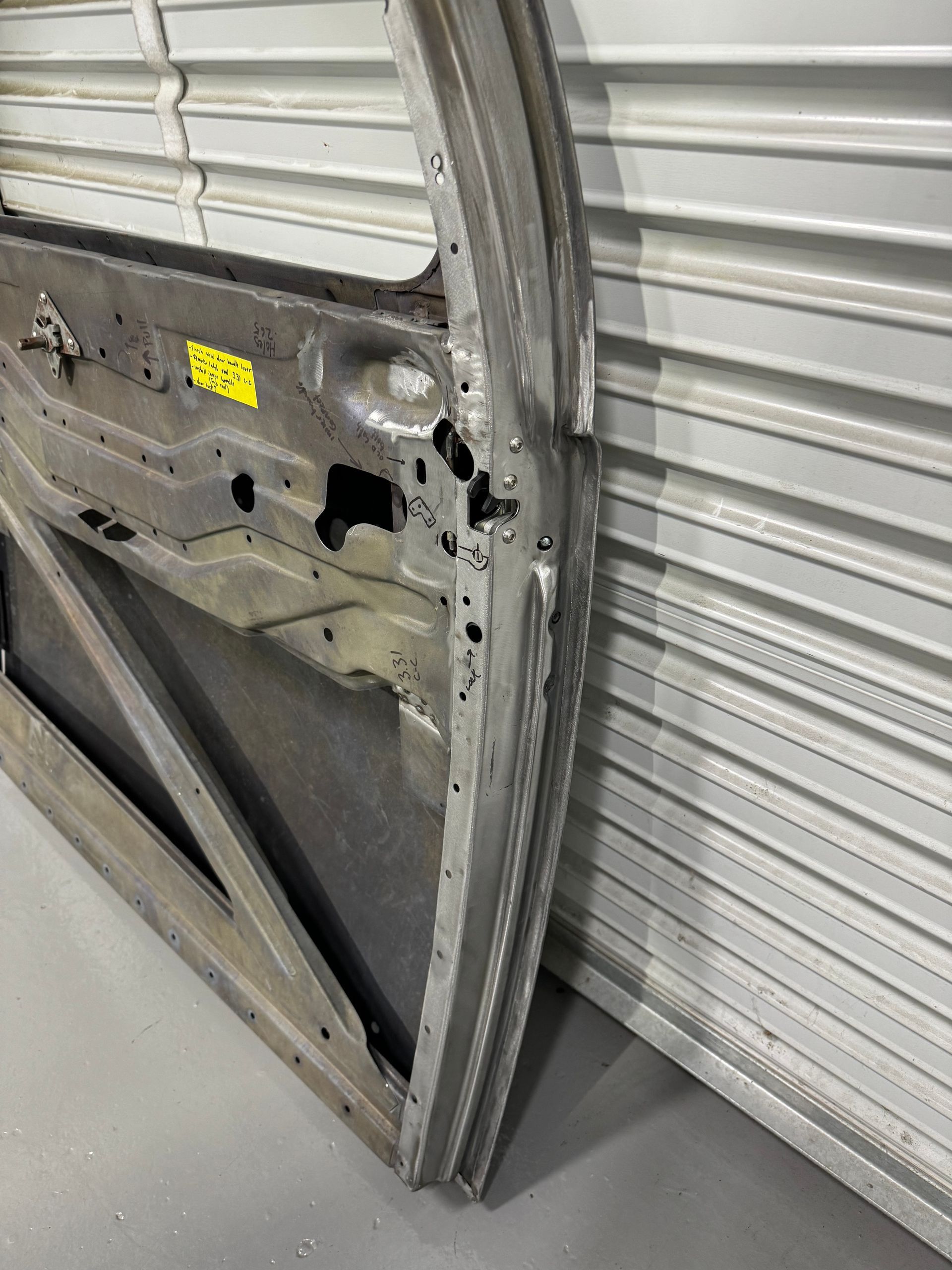 A car door is sitting on the floor next to a garage door.