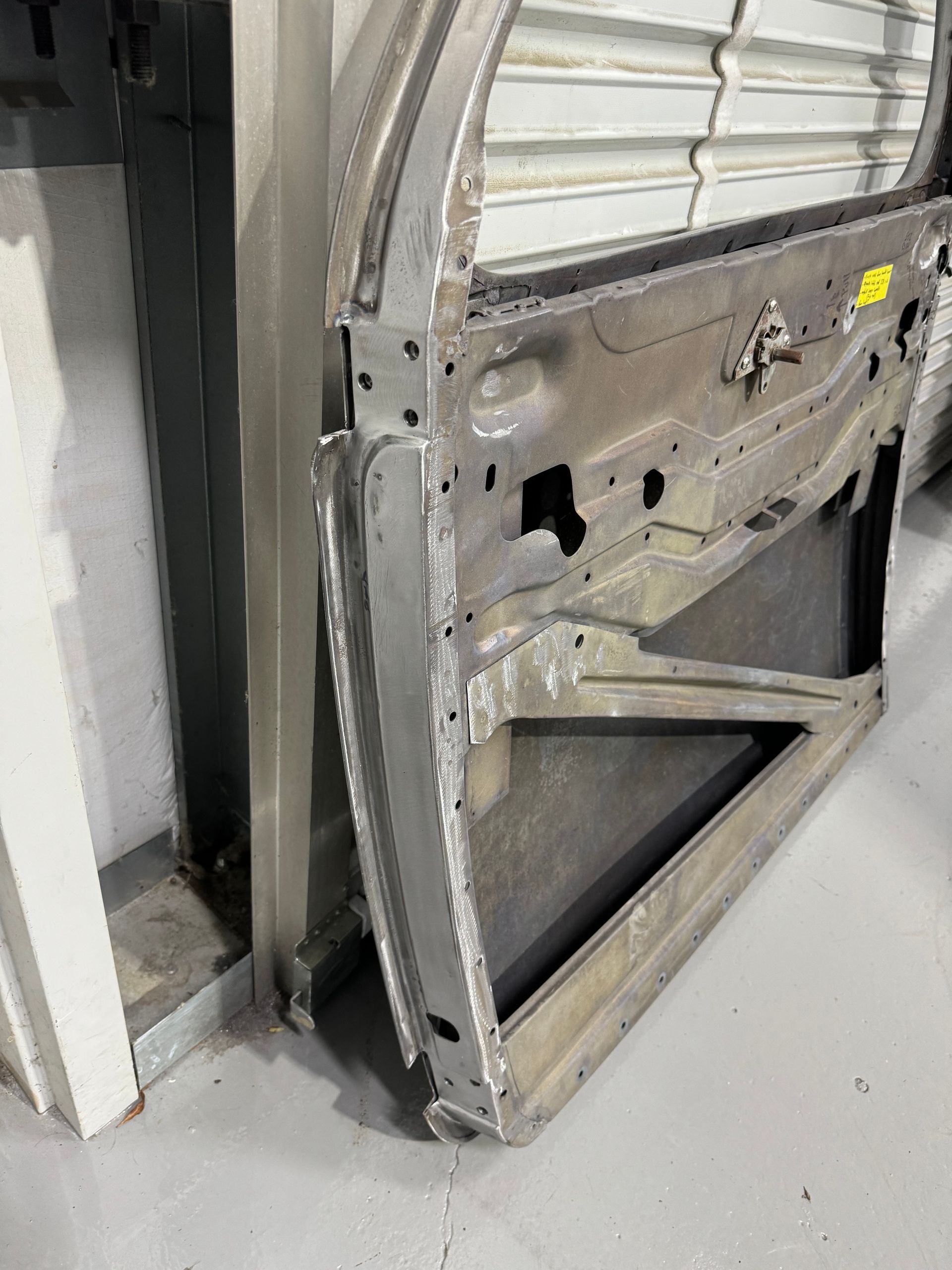 A metal door is sitting on the floor next to a wall.