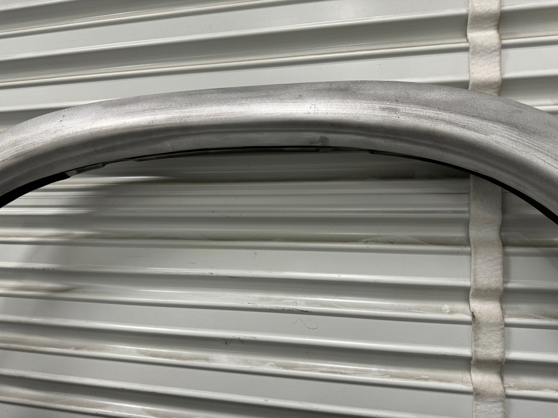 A close up of a metal fender on a white wall.