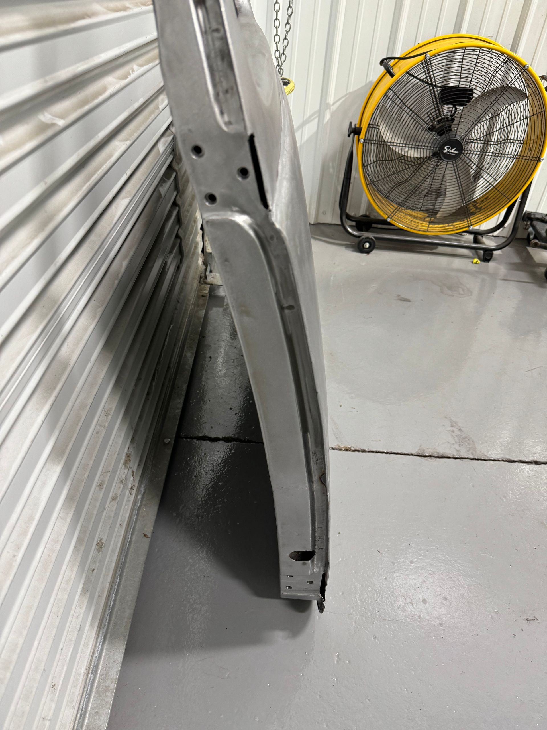 A yellow fan is sitting next to a piece of metal.