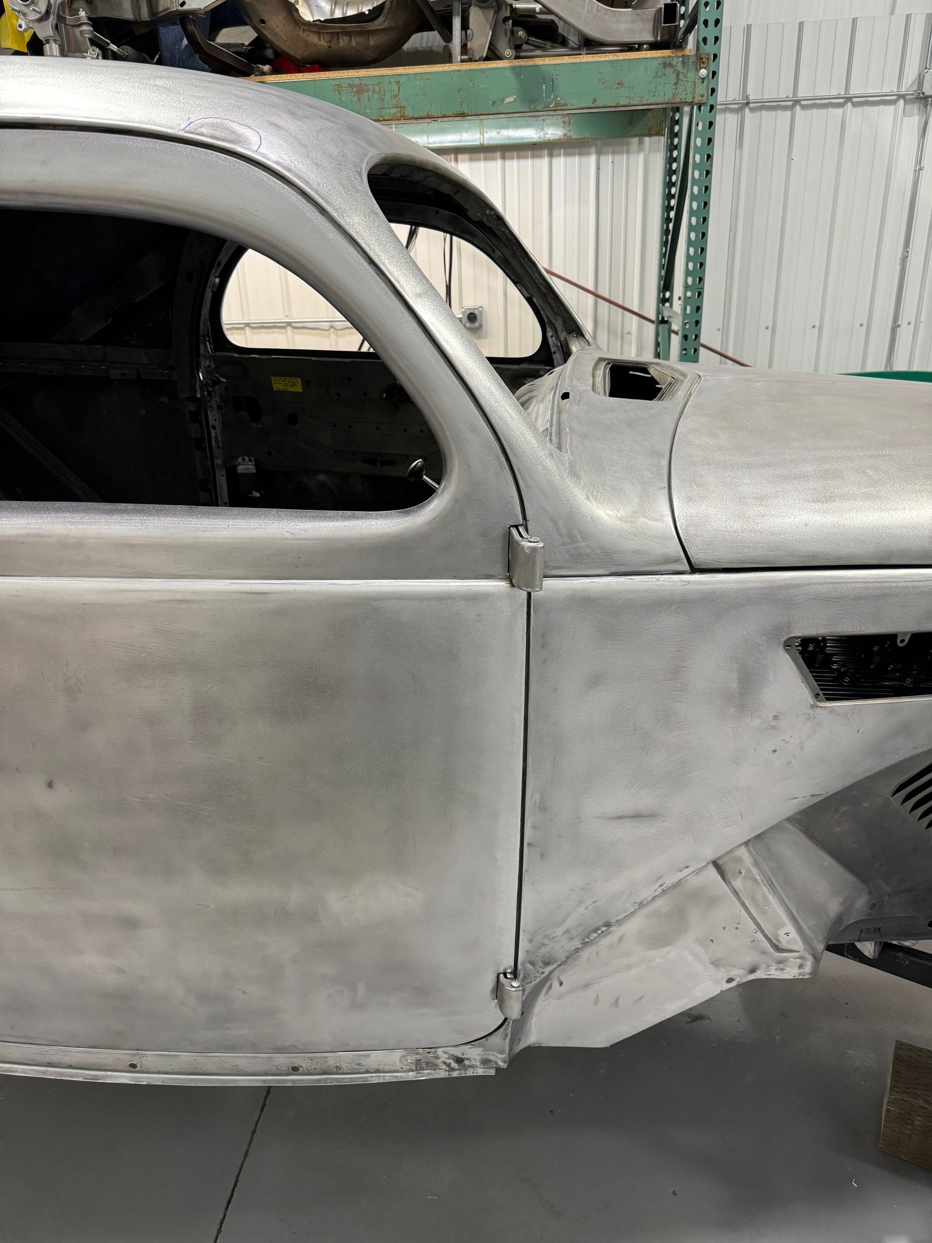 A silver car is sitting in a garage next to a shelf.