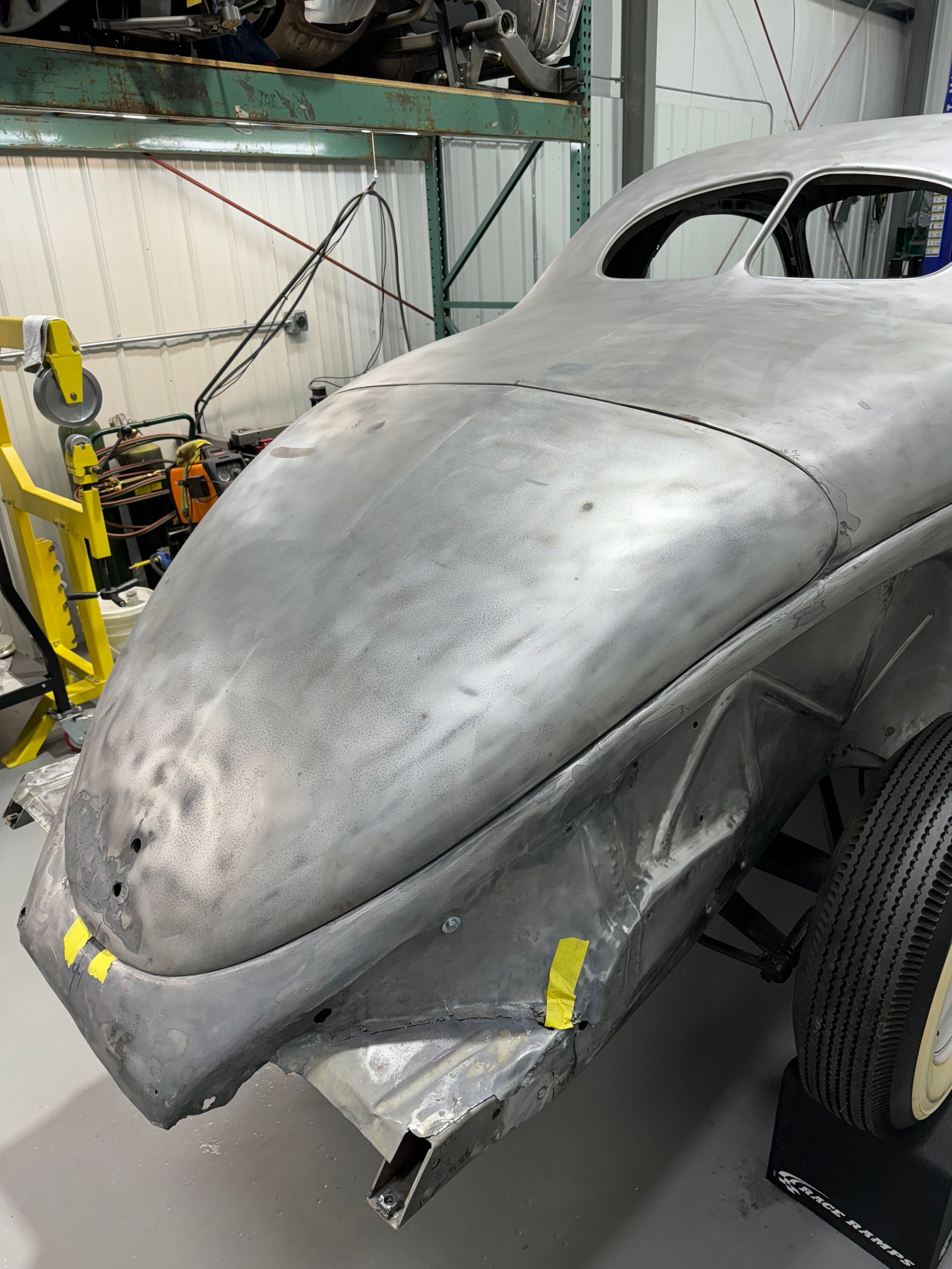 A silver car is being worked on in a garage.