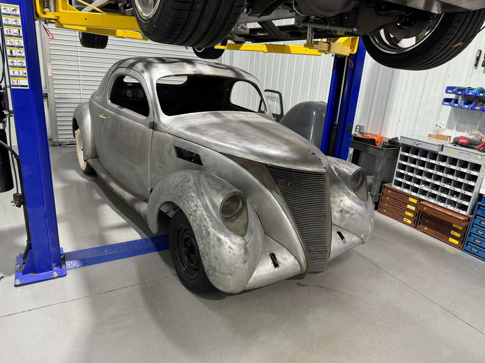 An old car is sitting on a lift in a garage.