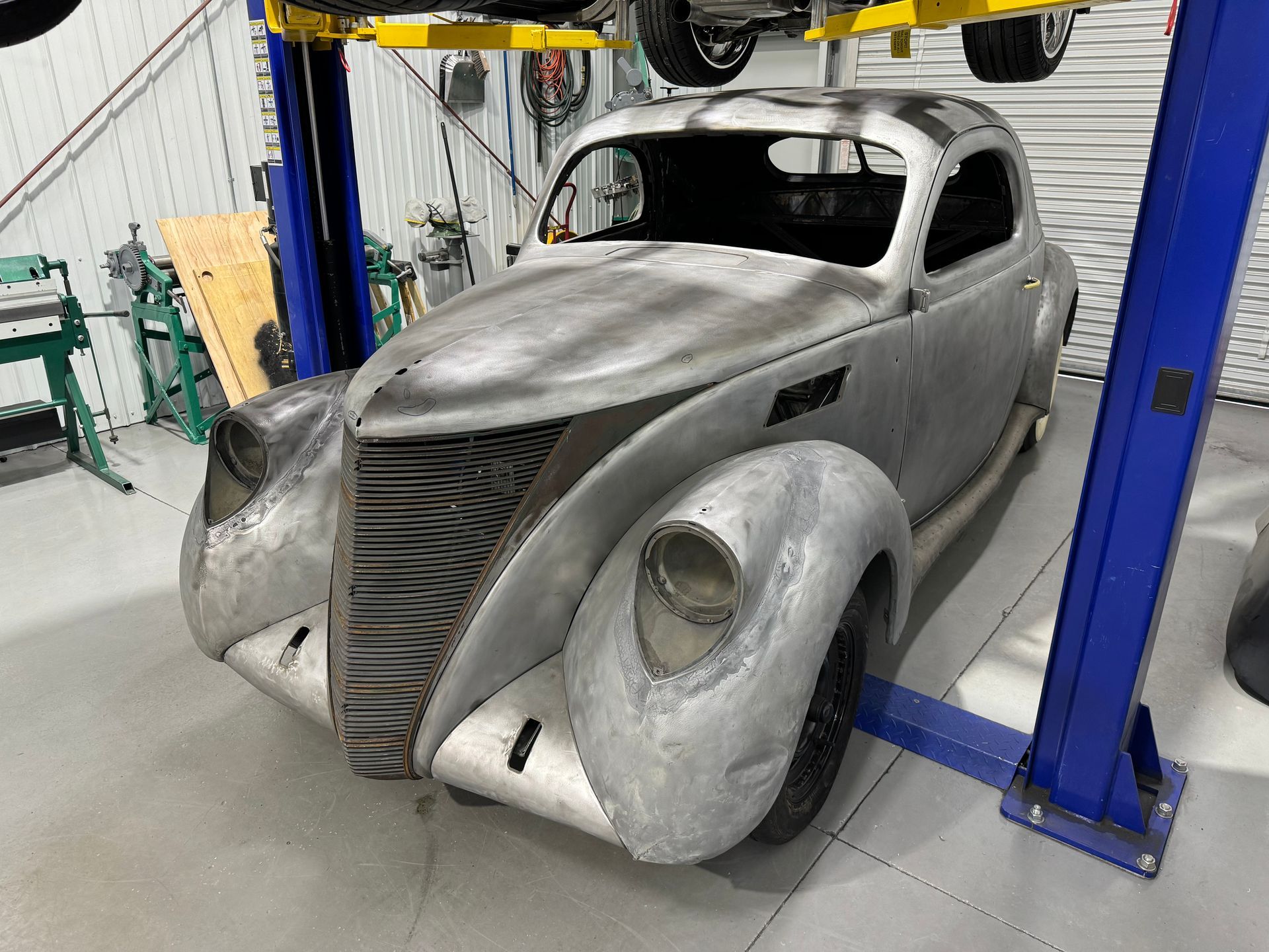 A silver car is sitting on a lift in a garage.
