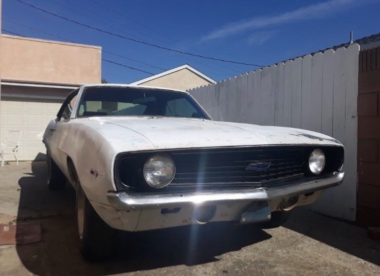A white chevrolet camaro is parked in a driveway